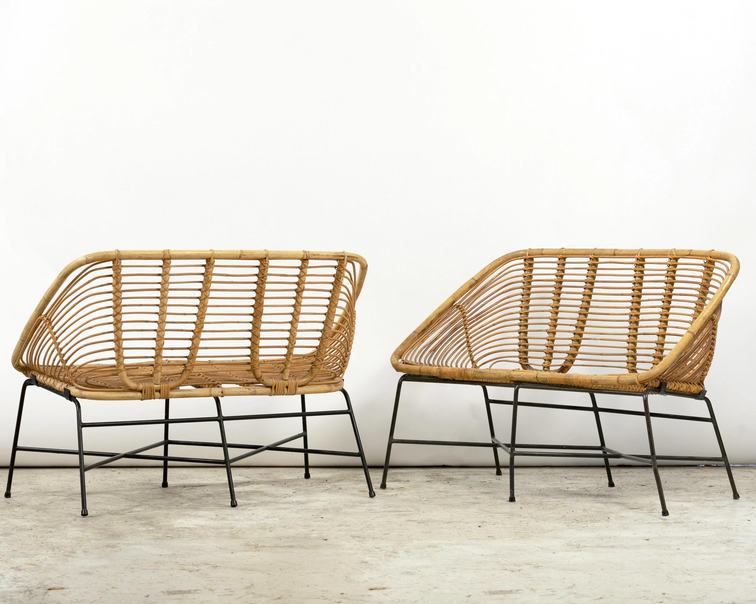 Pair of rattan and lacquered iron bench seats, France circa 1950. The one-piece basket-like seat is fixed to a base with six legs and two blackened iron struts. The end of each leg is fitted with a rubber tip.