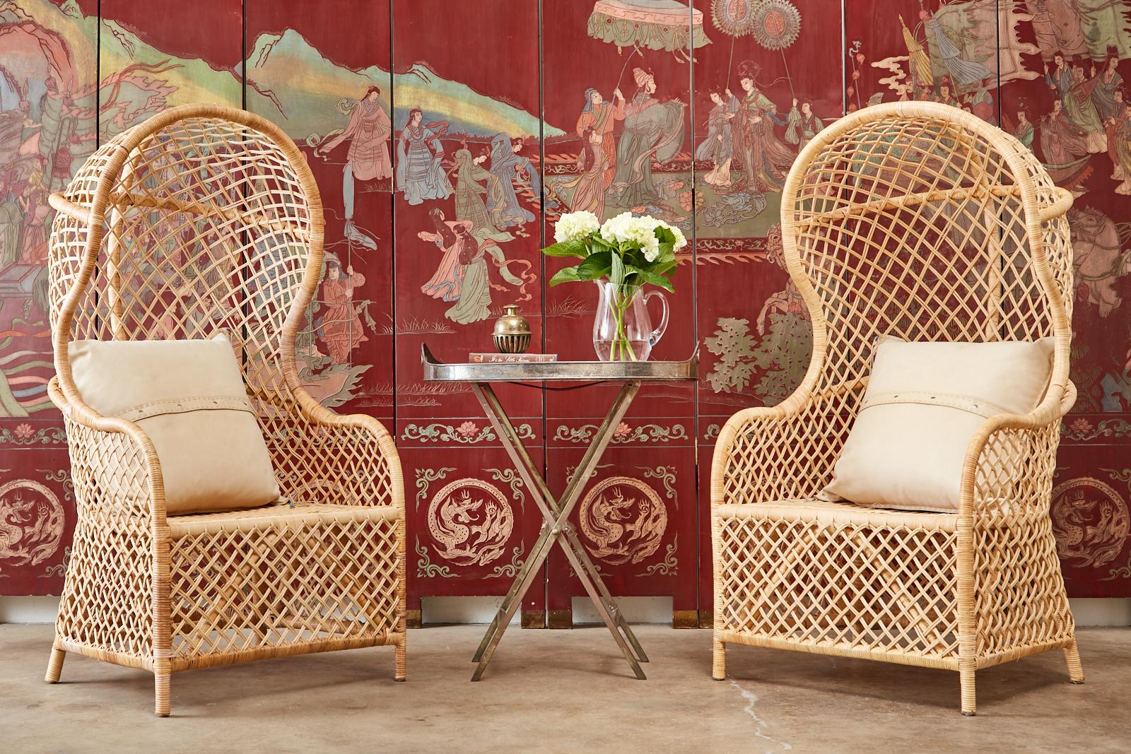 Stylish pair of hooded porters chairs or balloon chairs. Made in the organic modern style from rattan and wicker. The chairs have a birch wood frame covered in wicker or cane and fully enclosed with an open fretwork design of cross-hatch rattan.
