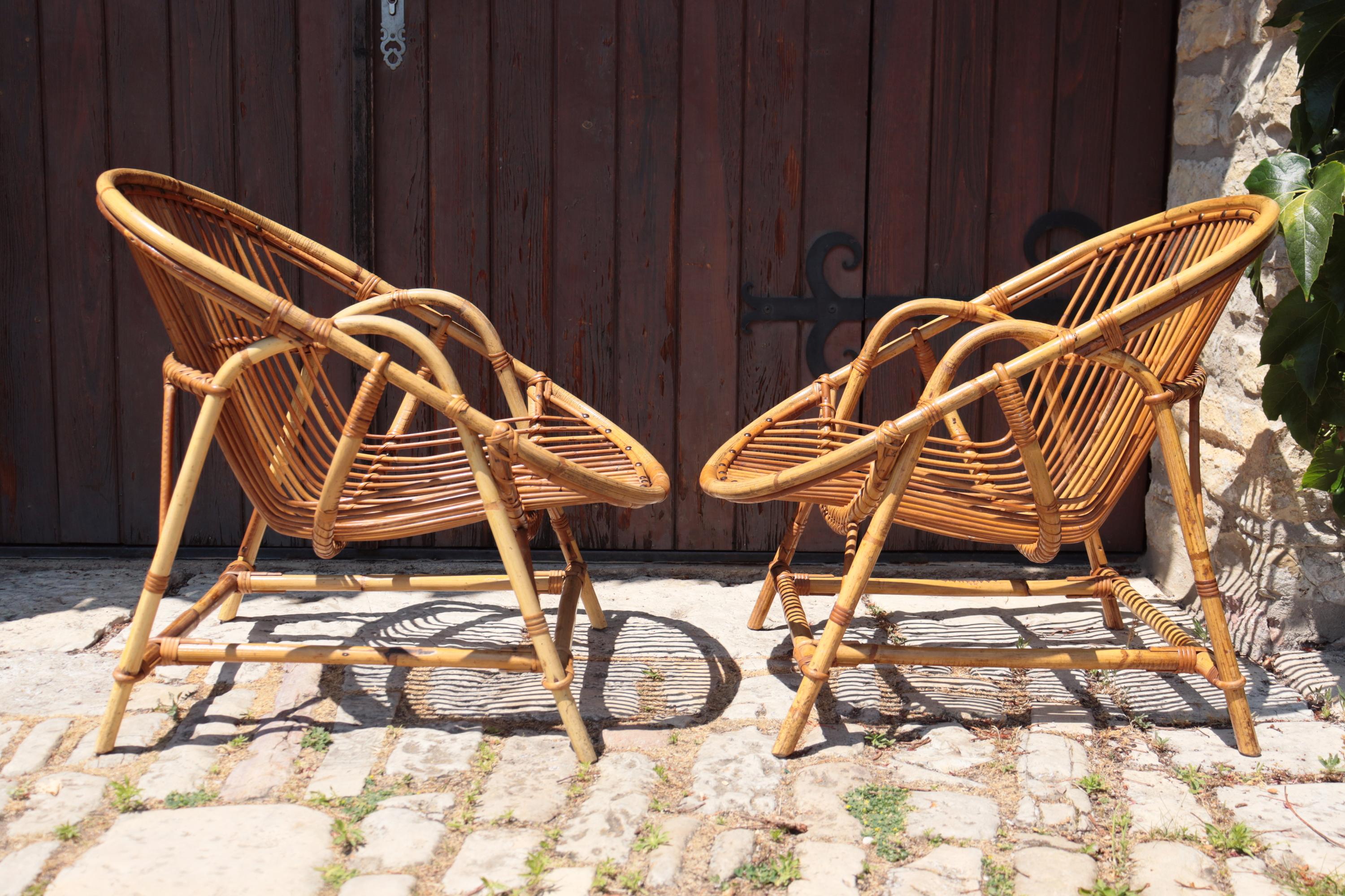 Elegant pair of natural rattan armchairs, work attributed to Adrien Audoux and Frida Minnet, emblematic designers of the French modern rustic movement of the 1940s-1950s. Tubular structure in curved rattan, seat and back composed of thin vertical