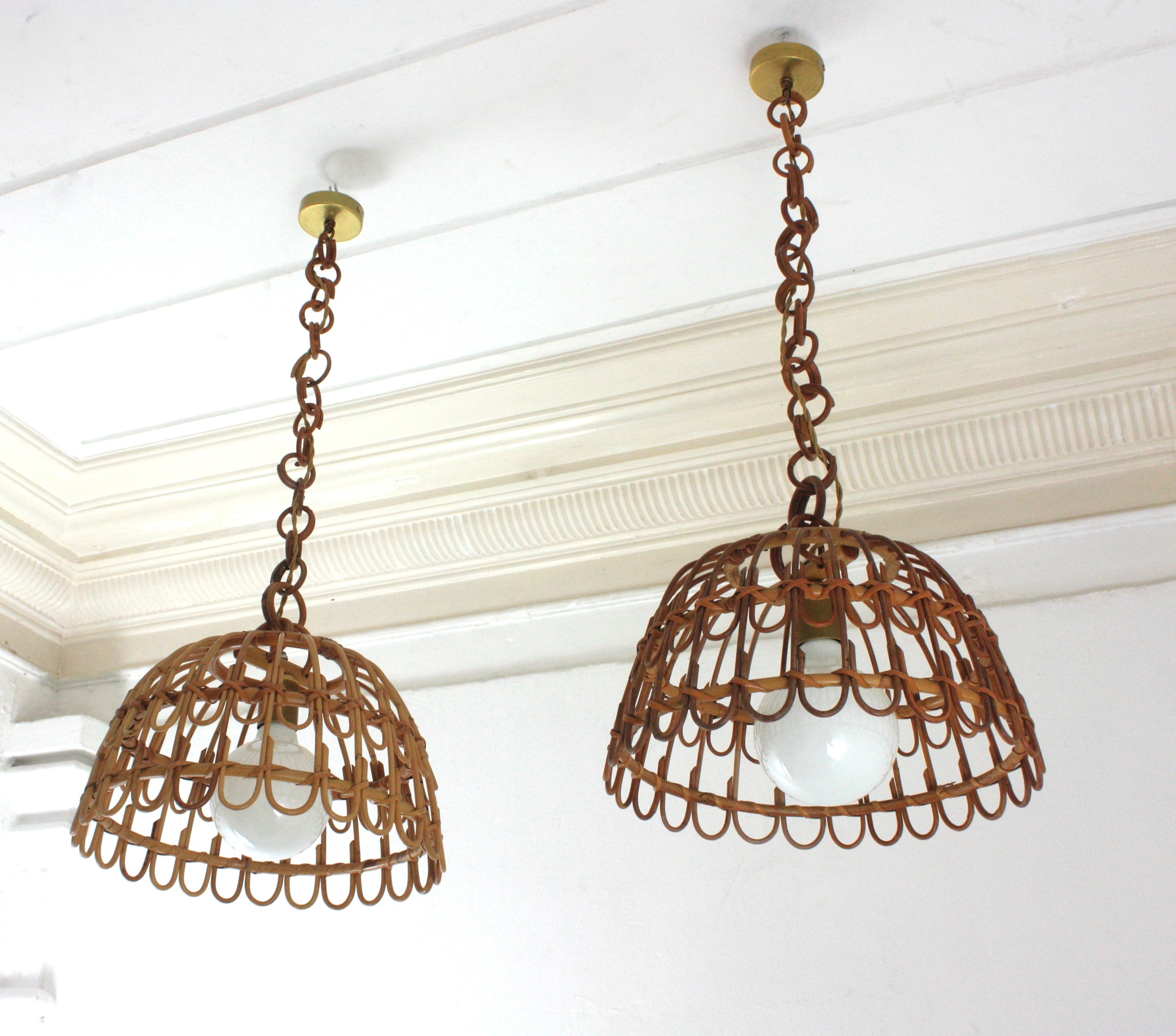 Spanish modernist rattan suspension lamps with bell shaped shades, Spain, 1960s.
Eyecatching handcrafted rattan pendant lights with geometric petal design.
They hang from chains with round rattan links and topped by brass canopies and brass covers