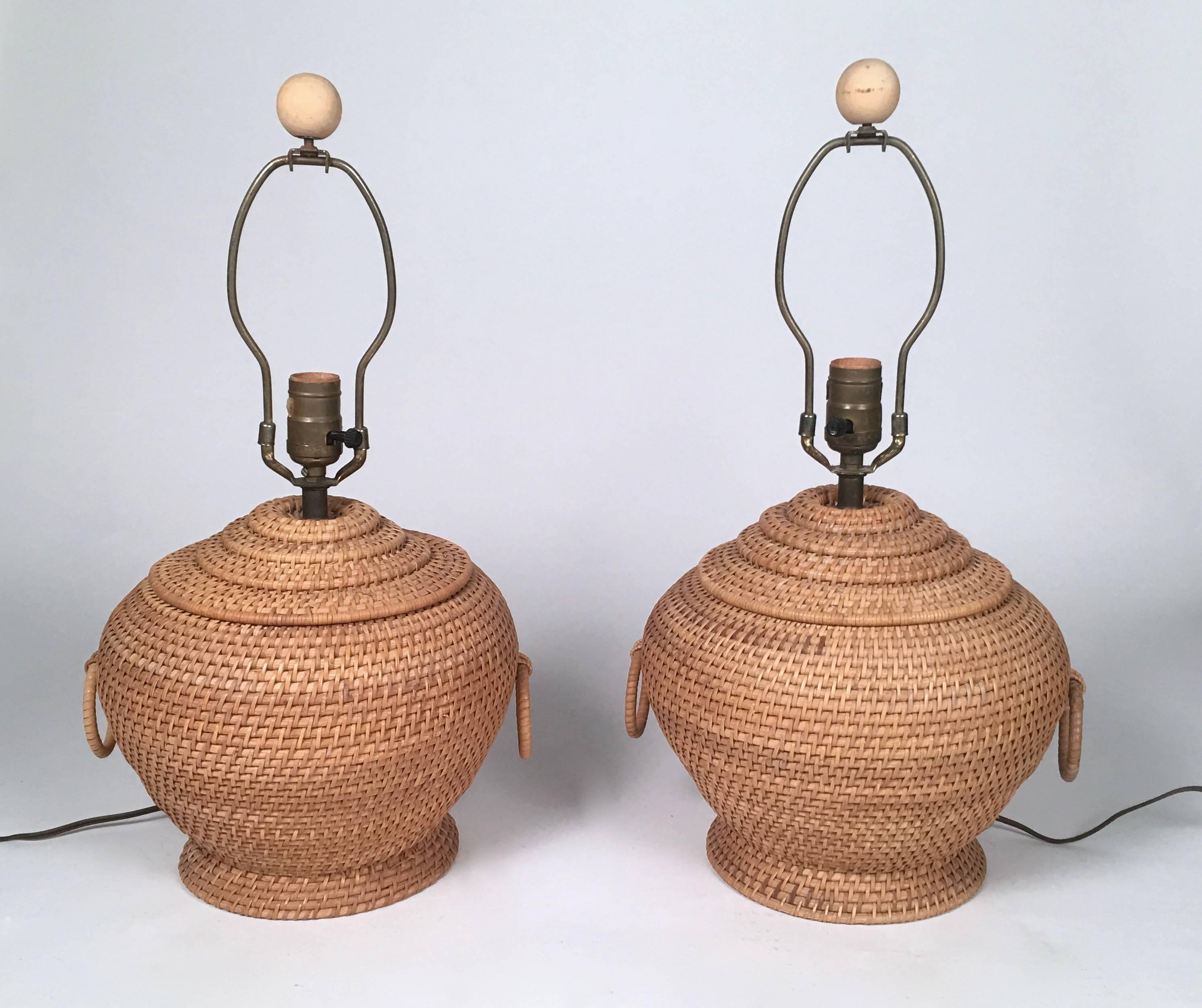 A pair of stylish vintage rattan lamps in the form of Chinese ginger jars with loop handles, of ovoid shape with high shoulders on a circular plinth base. Great condition. Newly re-wired.