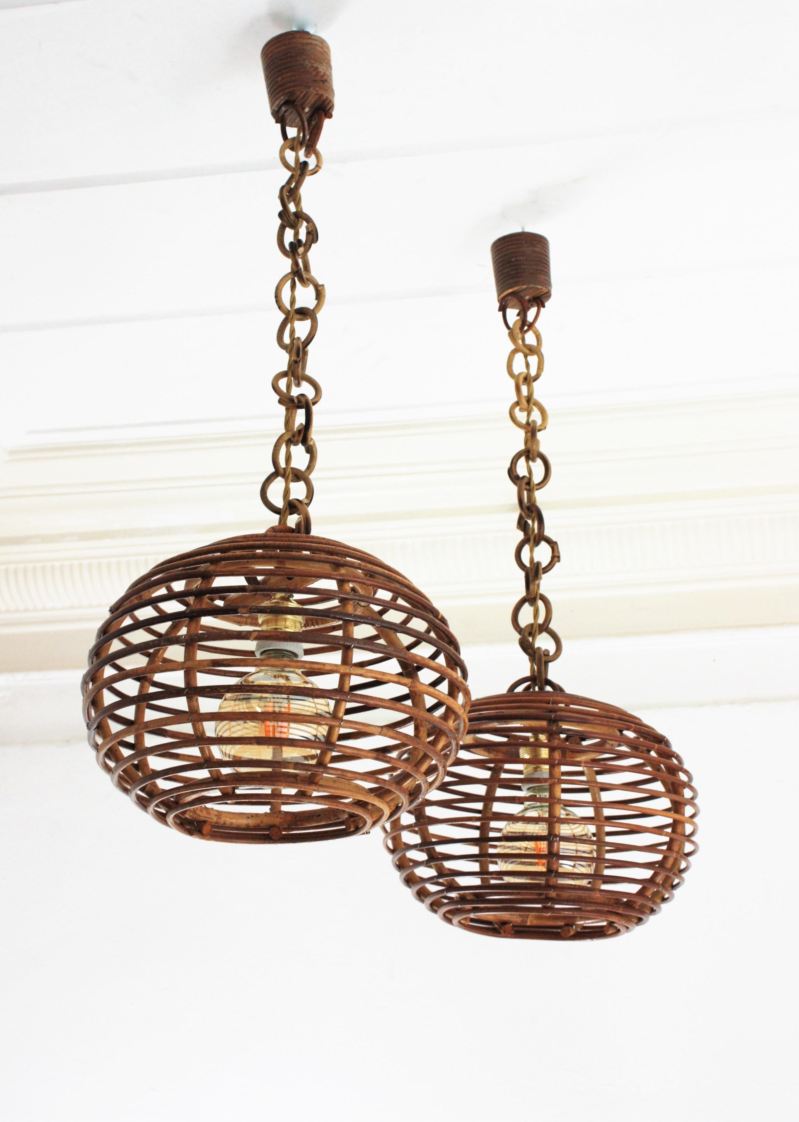 Eye-catching pair of rattan lanterns with globe or ball shaped lampshades, Spain, 1950-1960s.
These suspension lamps are entirely handcrafted with rattan, bamboo and wicker. The ball shaped shades hang from chains with round rattan links that can