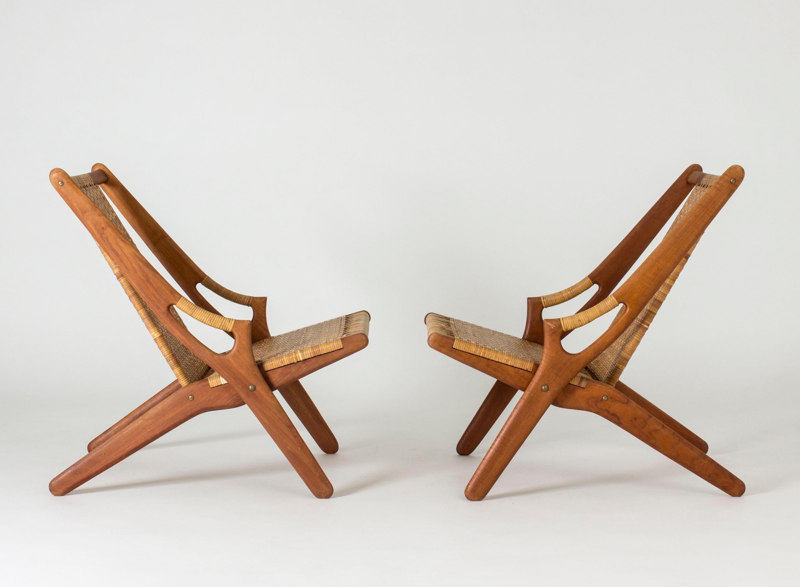 Pair of stunning teak and rattan lounge chairs by Arne Hovmand Olsen. Great silhouette with the sculpted handles often seen in Hovmand Olsen’s chairs.