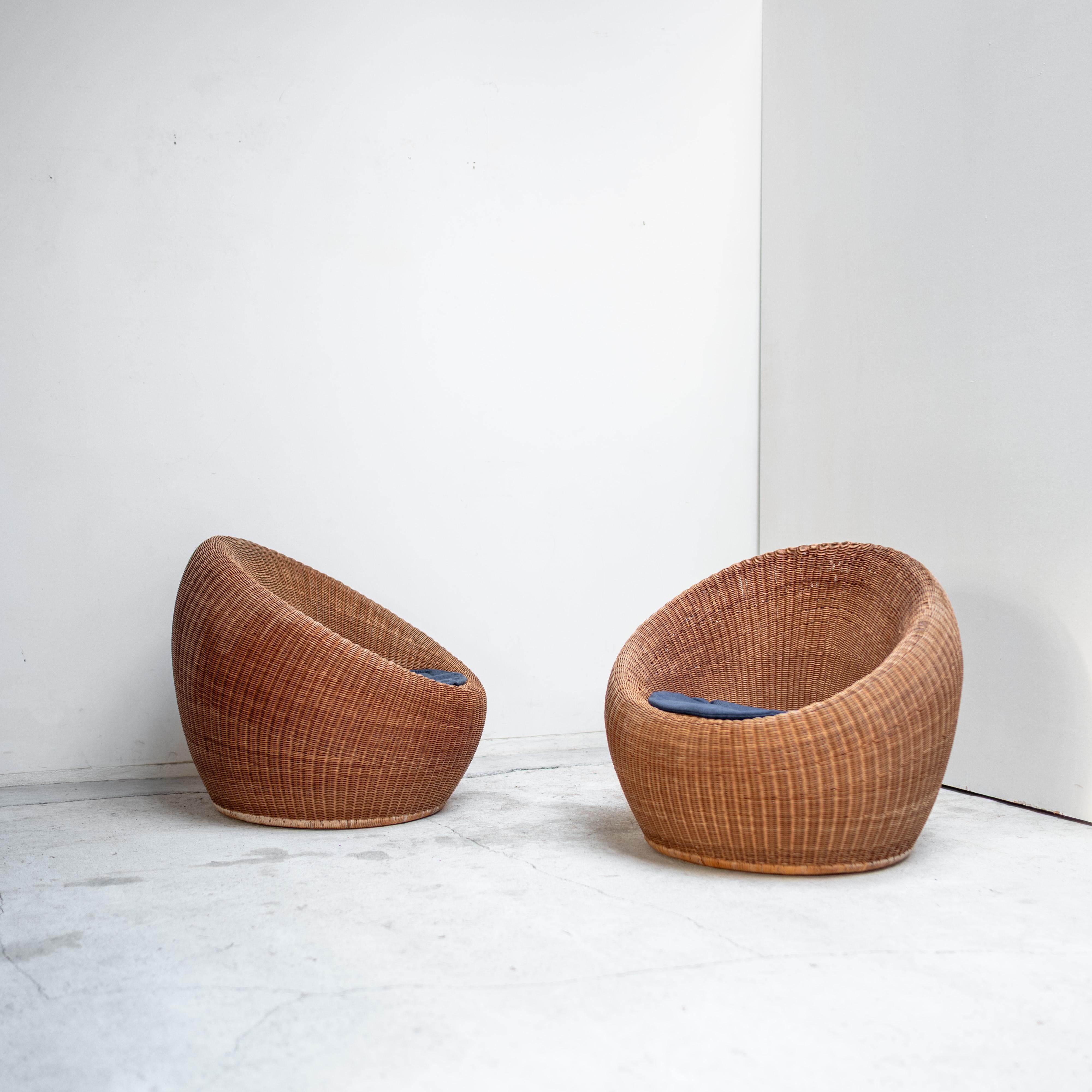 Ein skulpturales Paar Rattan-Loungesessel, entworfen von Isamu Kenmochi und hergestellt von Yamakawa Rattan, einem der führenden japanischen Hersteller von handgeflochtenen Möbeln. 

Die organisch abgerundeten Formen und das nahtlose Rattangeflecht
