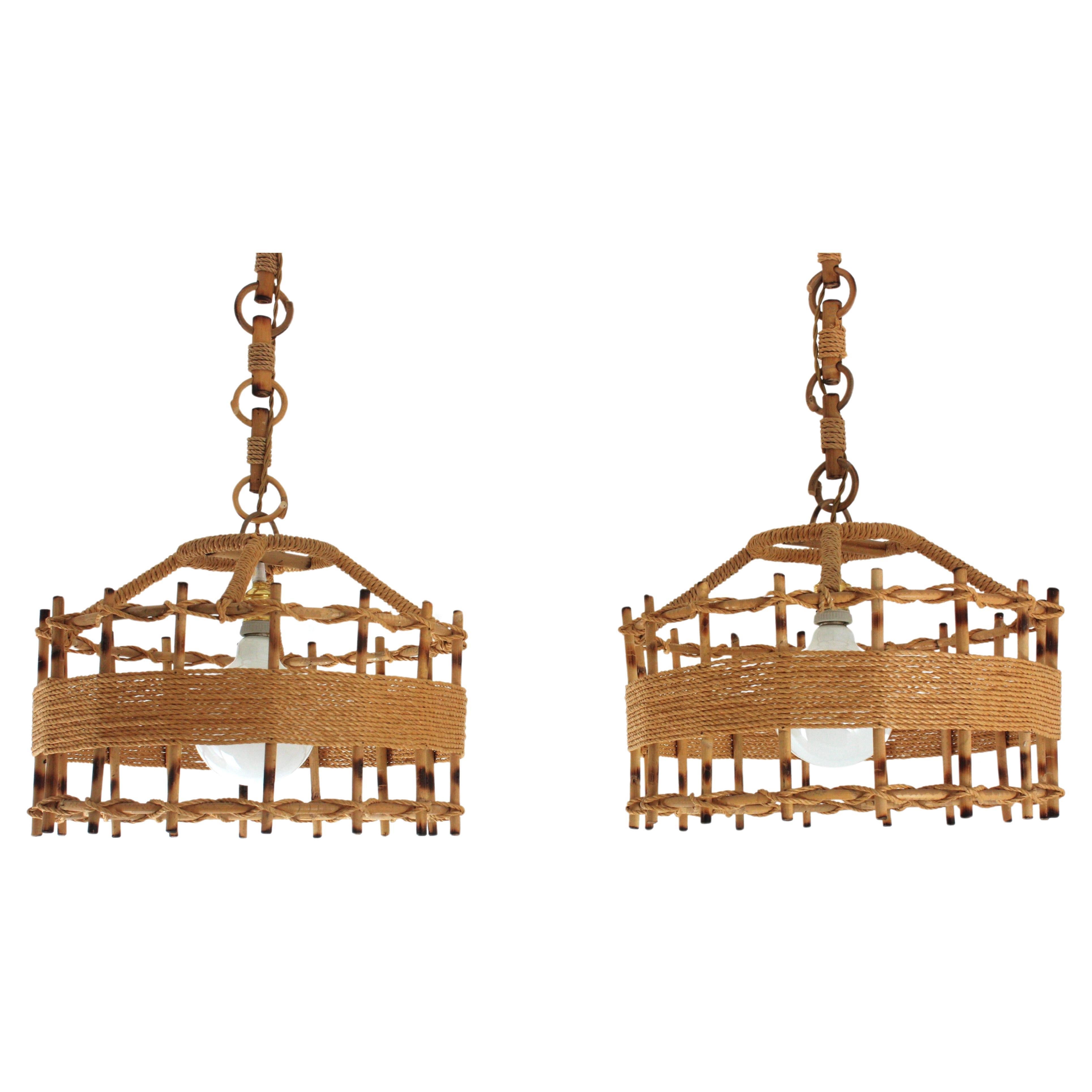 Pair of  handcrafted rattan drum shaped ceiling suspension lamps in rope and rattan. Spain, 1960s
This large artisan lanterns has an eye-catching design featuring a cylindrical structure made of rattan sticks wraped and detailed with jute rope.