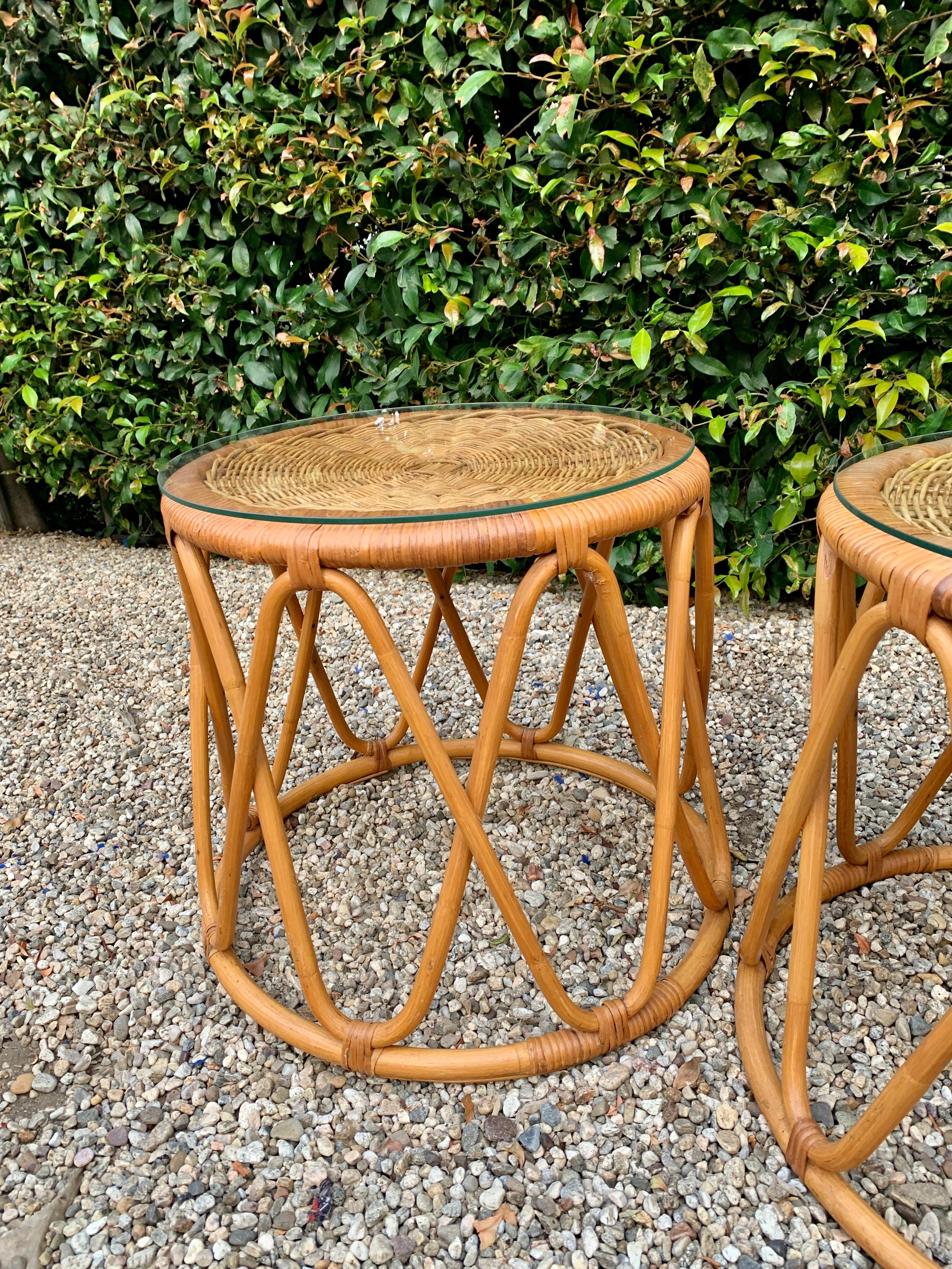 A pair of Bent rattan tables - a very pleasing criss-cross pattern and slightly larger at the bottom. Each table has a round piece of glass. These, with a cushion would also be very functional as an ottoman.