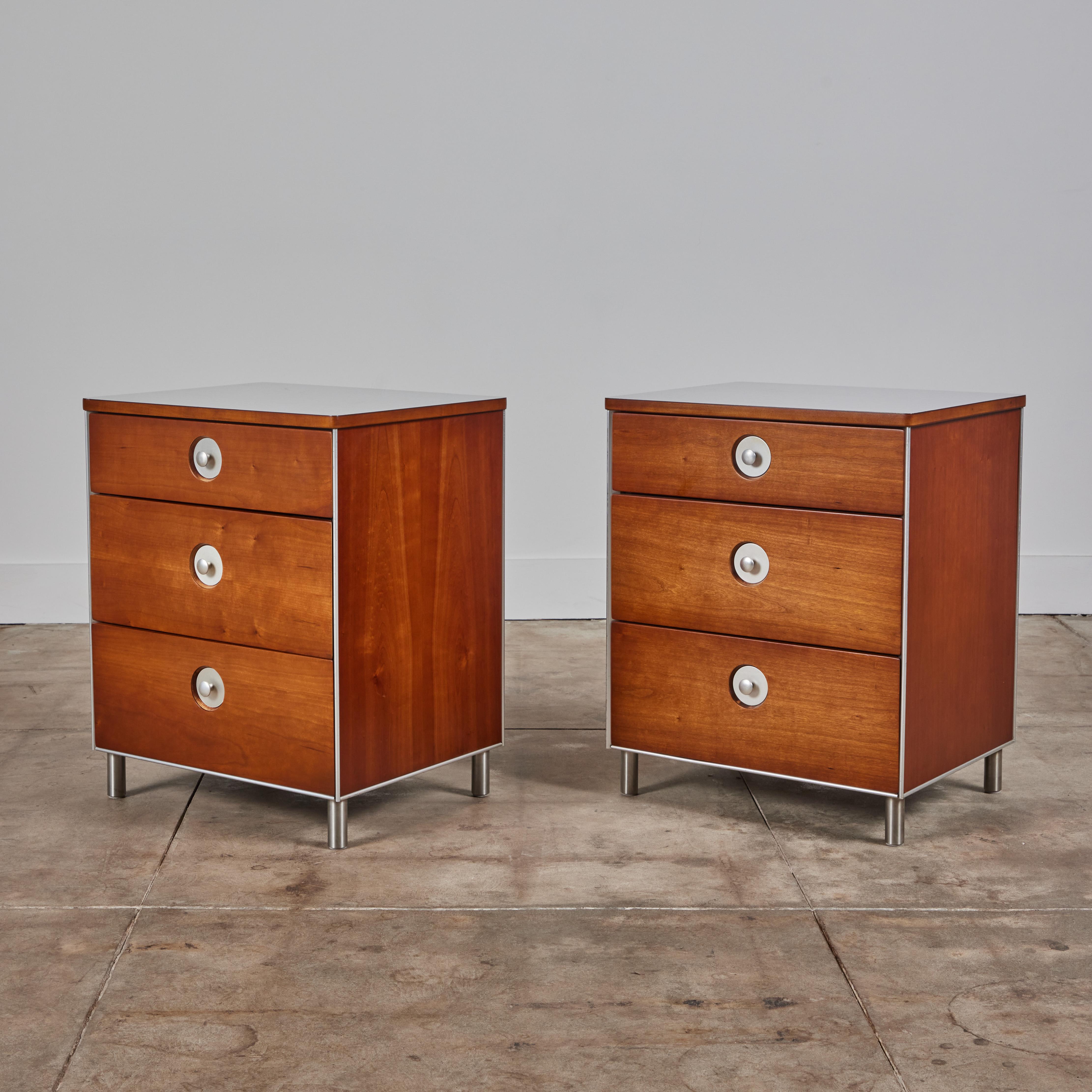 Pair of cherry nightstands by Raymond Loewy for Hill-Rom Company, c.1950s, USA. This industrial design features off white laminate tops that resemble a textured linen design. Each nightstand has three drawers with round aluminum drawer pulls. The