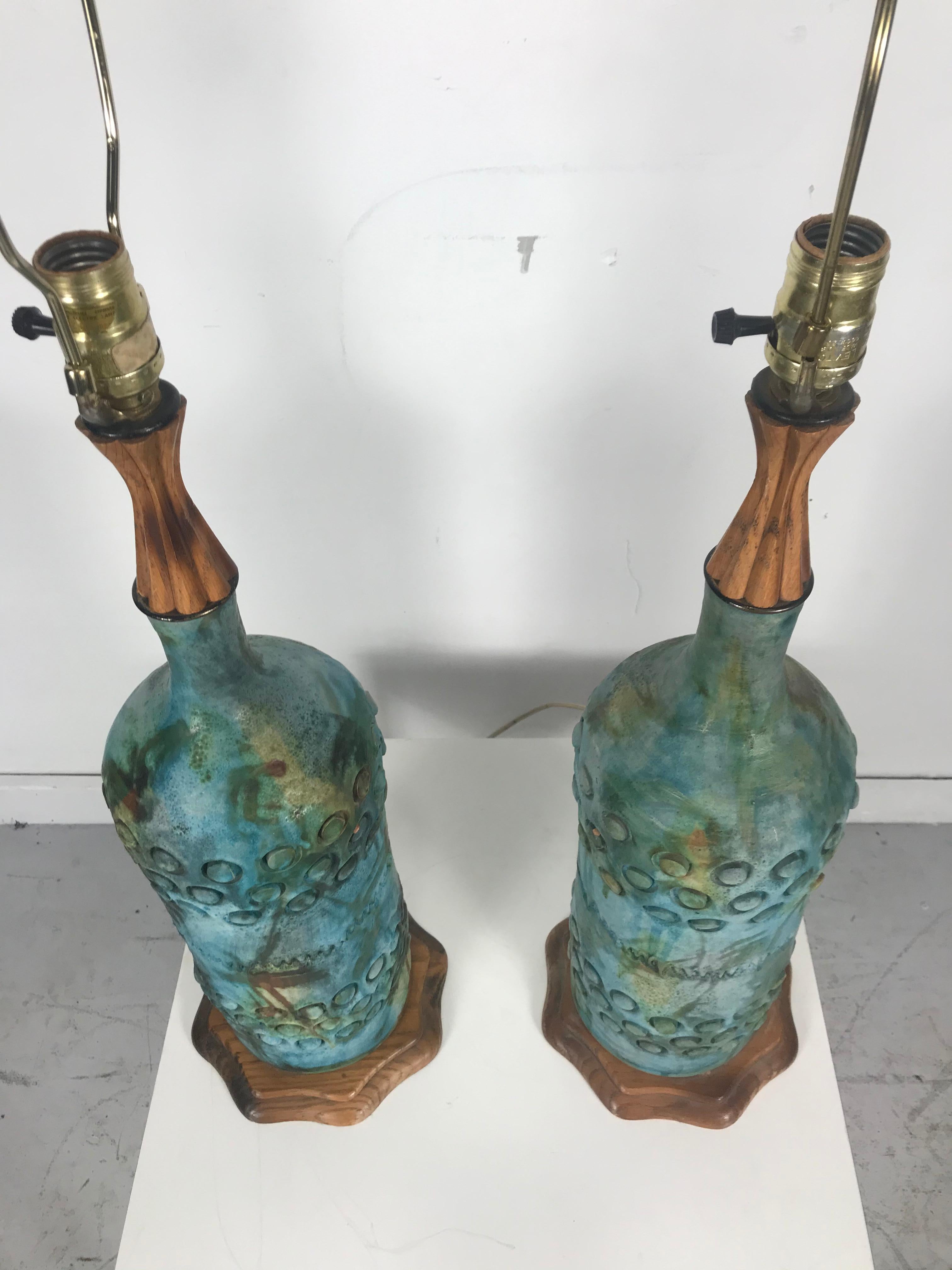 Pair of Raymor Italian ceramic pottery lamps by Alvino Bagni. Unusual form, beautifully textured, glazed, carved wood detailing.
