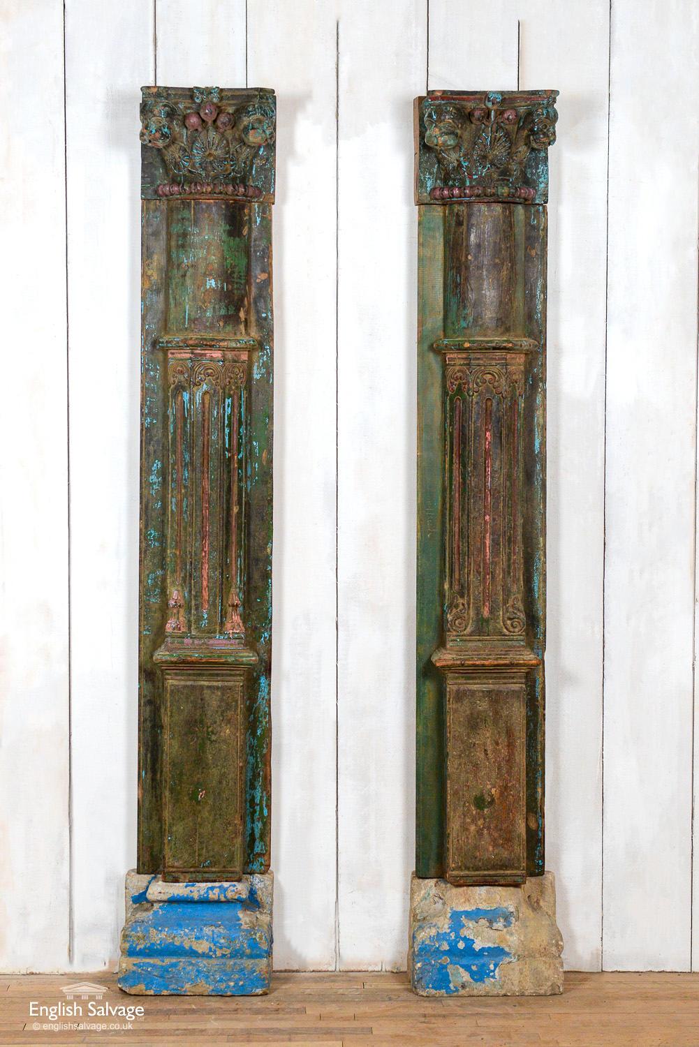 Reclaimed Indian pillars in three parts with stone bases, teak columns and carved teak capitals. The stone bases have remnants of blue paint and the stone has softened with age. The columns are carved in three sections: the bottoms with a square