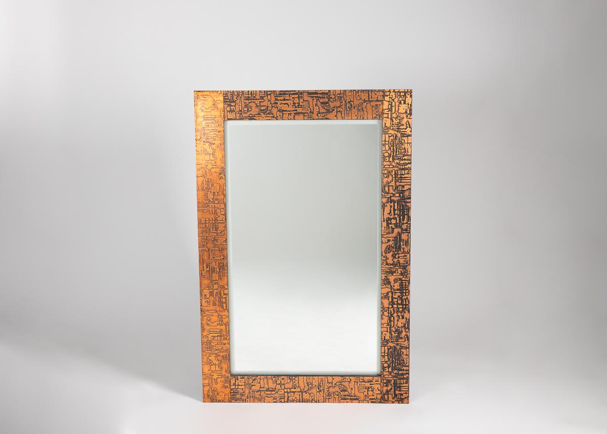 Une paire de grands miroirs rectangulaires, encadrés en bois avec une finition géométrique de couleur cuivre dans un motif géométrique répétitif et entrecroisé.