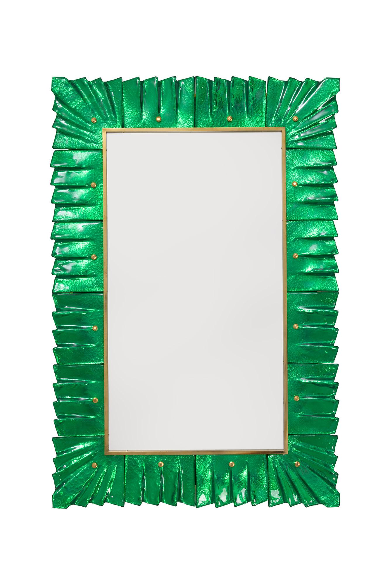 Pair of Murano emerald green glass framed mirrors, in stock.
Rectangular mirror plate surrounded with undulating glass tiles in emerald green color held by brass cabochons. 
Handcrafted by a team of artisans in Venice, Italy. 
Can be easily hung