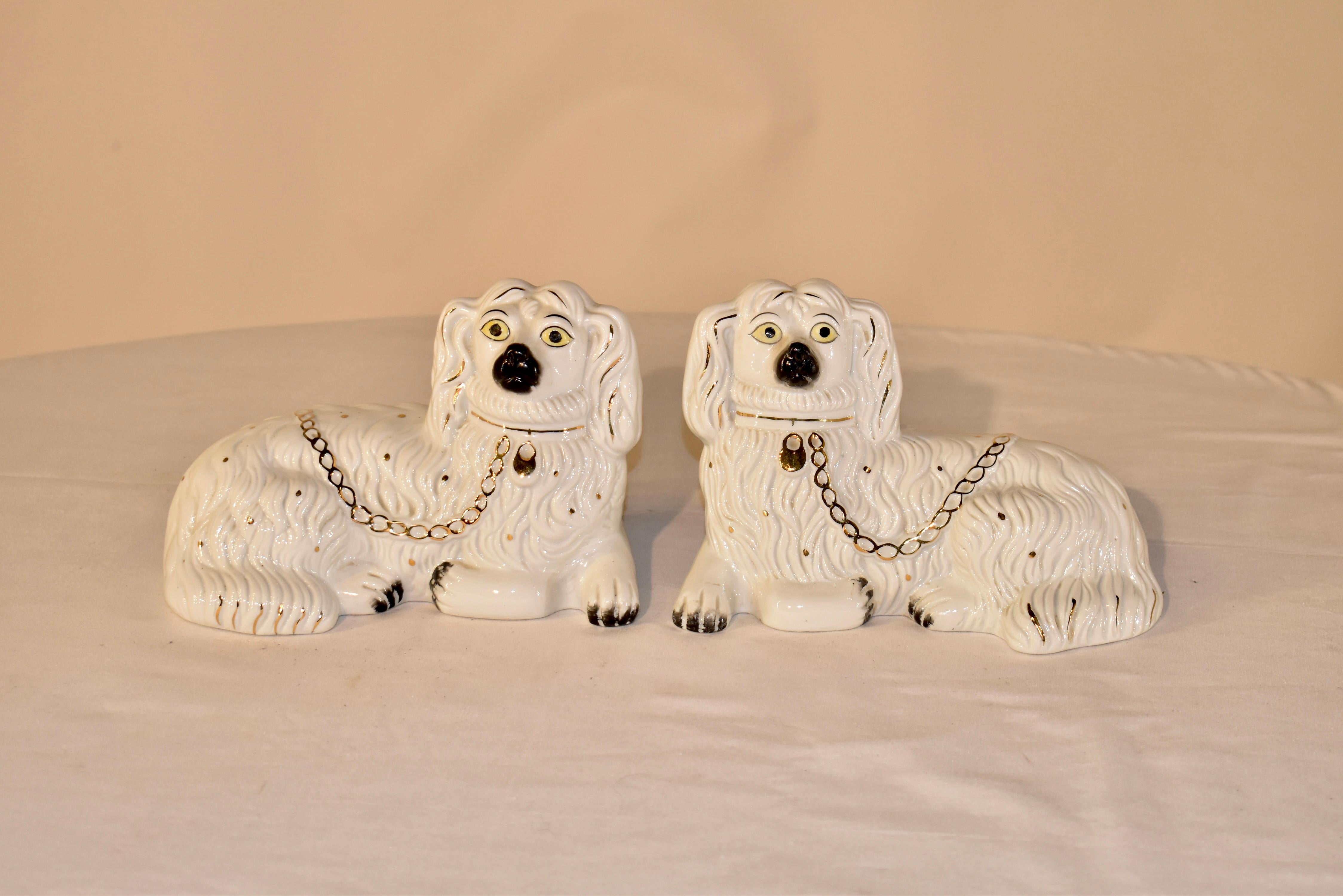 Pair of recumbent ceramic spaniels from the Staffordshire region of England. They have lovely faces which are hand painted and gold painted collars and chains. Nice mold detailing and gold embellishments throughout.