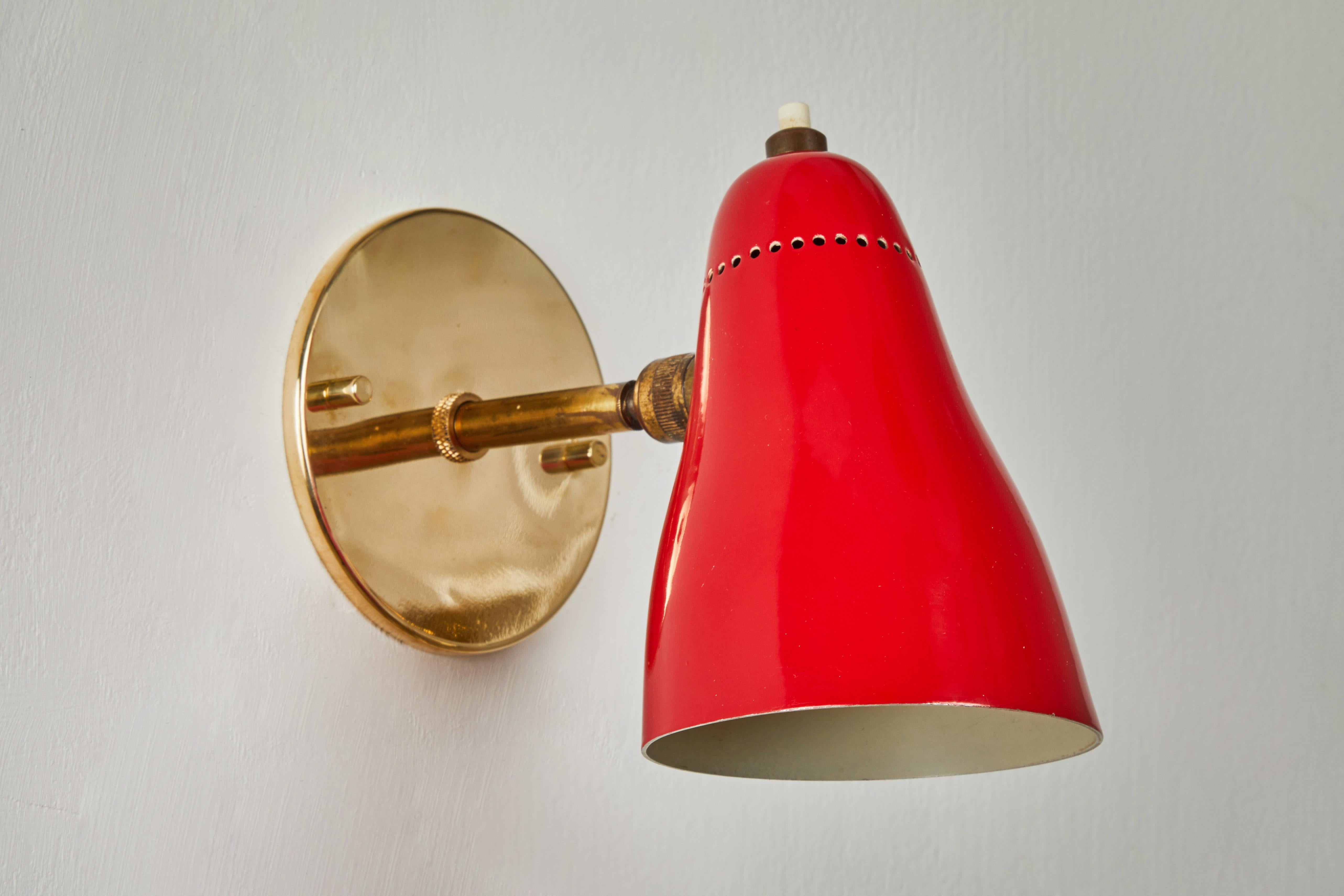 Pair of Red 1950s Giuseppe Ostuni articulating sconces for O-Luce. Executed in brass and red painted aluminum with perforated shade. Sconces pivot up/down and left/right on two separate ball joints. Original on/off switch on top of lamp. Wired for