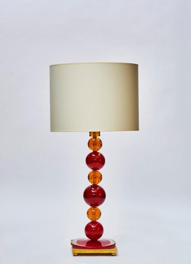 Pair of table lamps made of a brass foot and a stack of Murano glass balls tinted in red and orange.