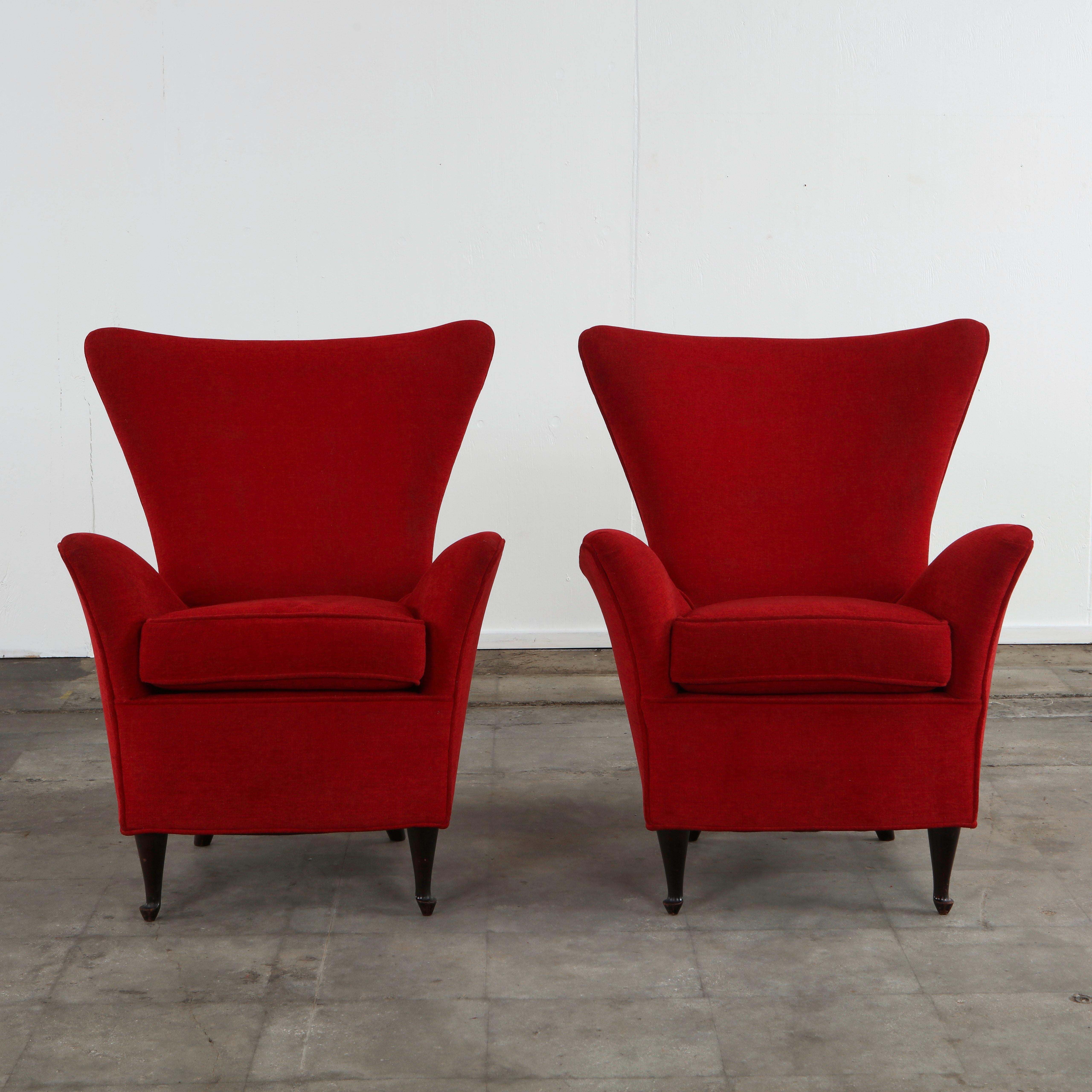 Elegant pair of 1950s Italian lounge chairs featuring sculptural, wing-back silhouettes and gently flared armrests. The generous, high backs create a refined sense of presence, while the deep seats and loose cushions offer comfort and support. Newly