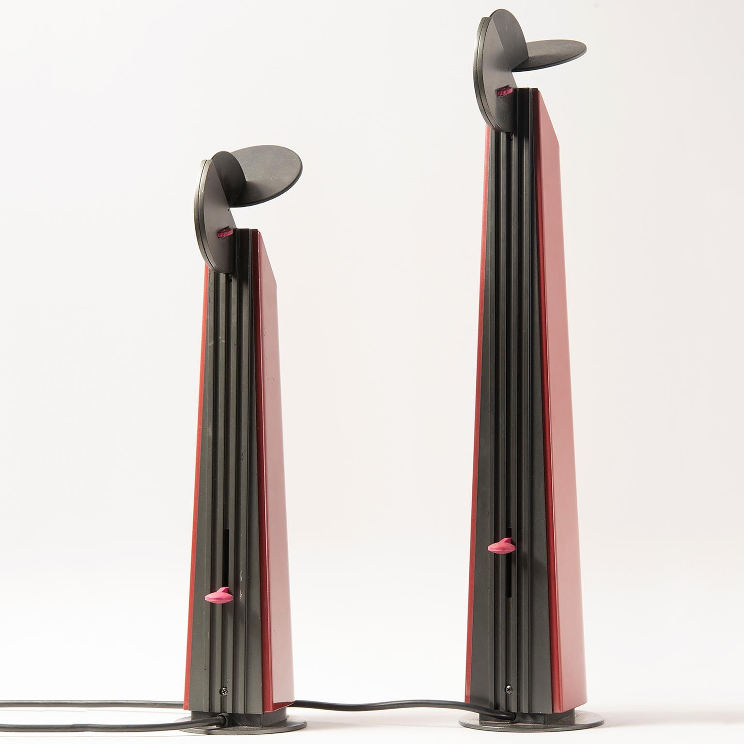 Two Gibigiana lamps from Italy designed by Achille Castiglioni for Flos feature dark red bases with black tops, circa 1980s. The Gibigiana lamp casts light in a very specific spot, directing it through a special reflective mechanism. The designer