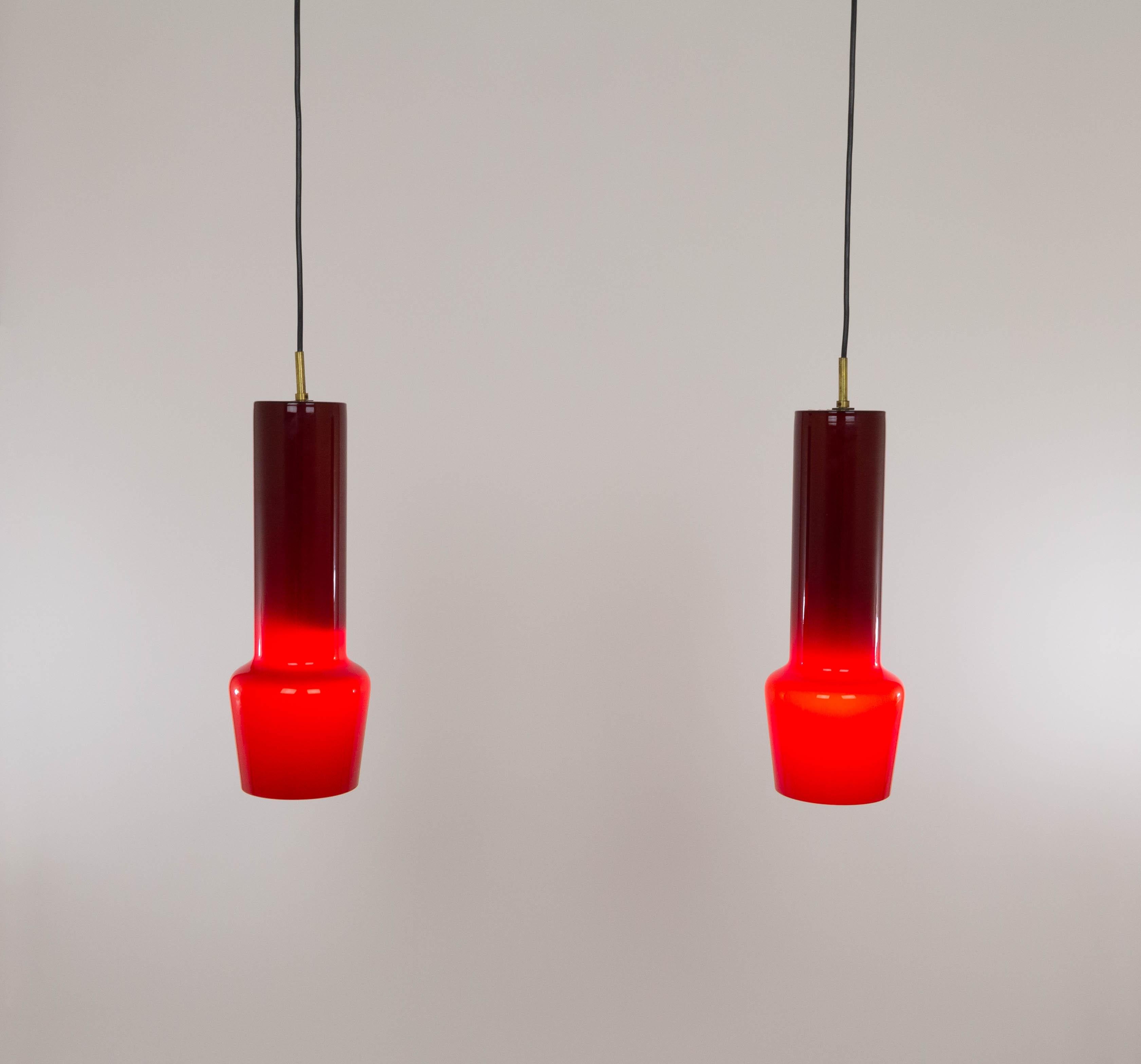 Paire de pendentifs en verre rouge n° 011.11 soufflé à la bouche, conçus par Massimo Vignelli au début de son impressionnante carrière de designer et exécutés par le spécialiste du verre de Murano, Venini. L'une des lampes les plus caractéristiques