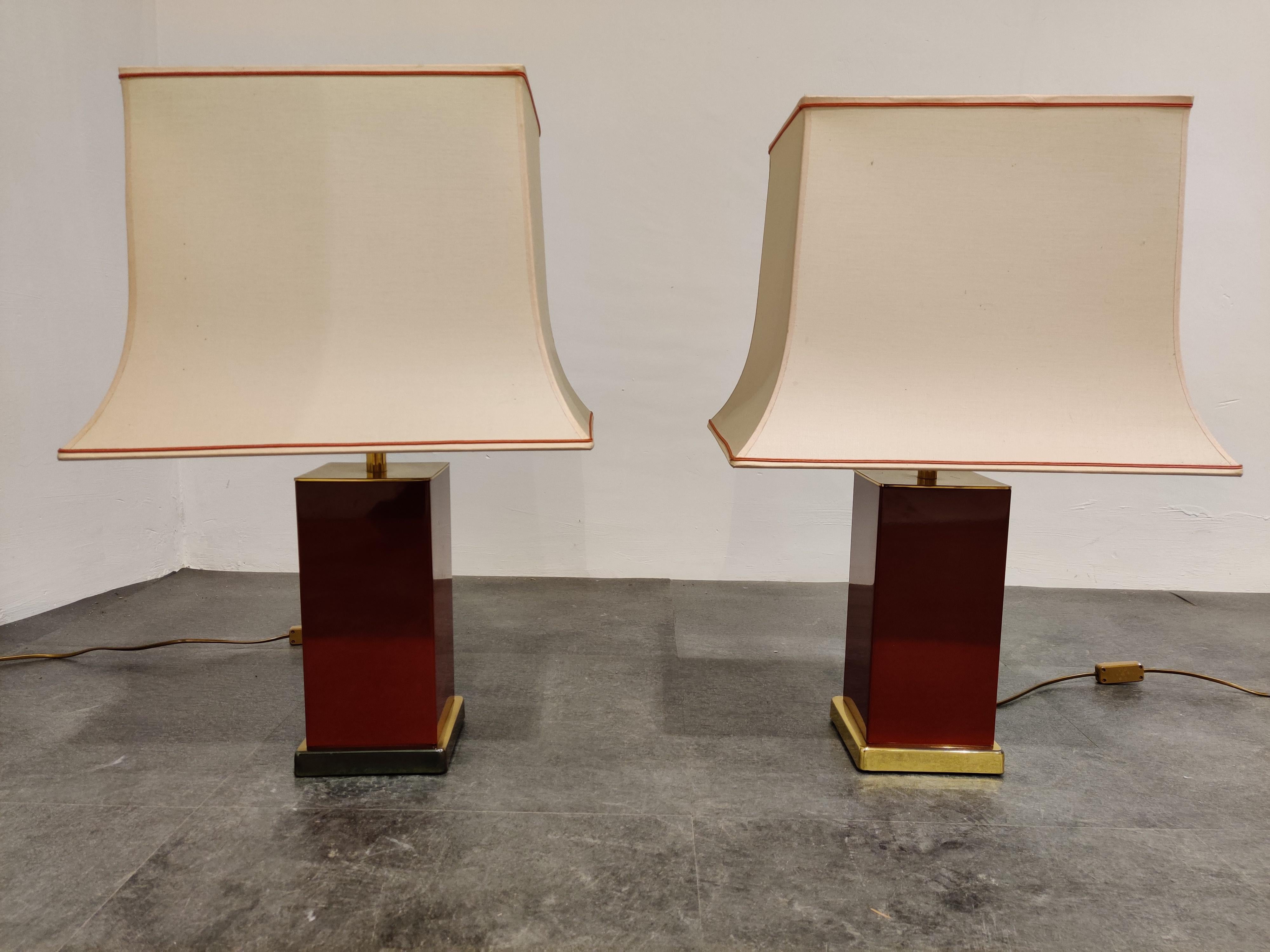 Pair of charming red lacquered table lamps on brass bases by Jean Claude Mahey.

The pair of lamps come with their original shades with red lining.

Beautiful red or Bordeaux color and minor patina on the brass bases.

1970s,