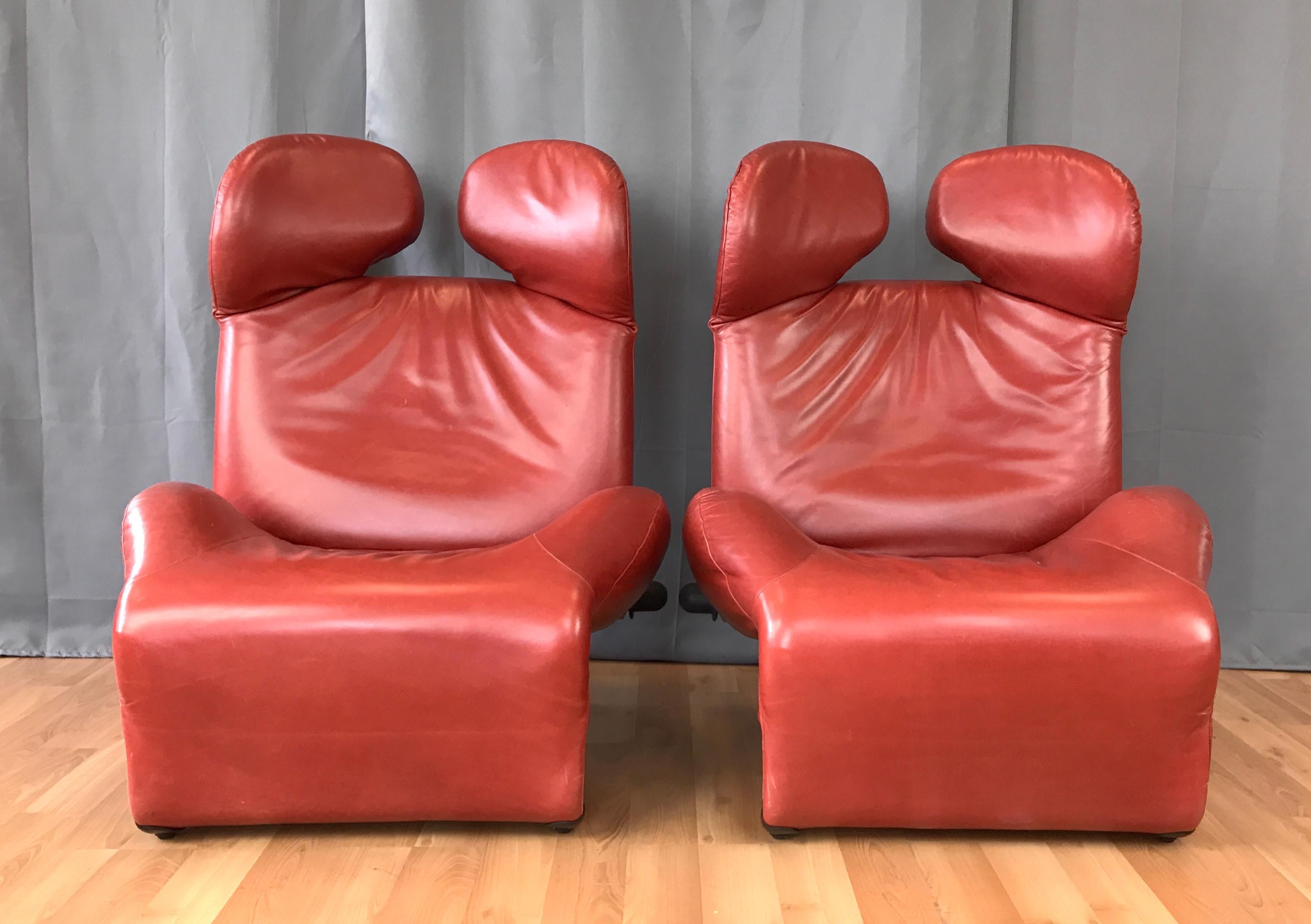 An early 1980s pair of sensuous cranberry red leather Wink lounge chairs by Toshiyuki Kita for Cassina.

Ingeniously adaptable, adjustable, and convertible, with independently moveable headrests, a knob-controlled reclinable back, and a cantilevered