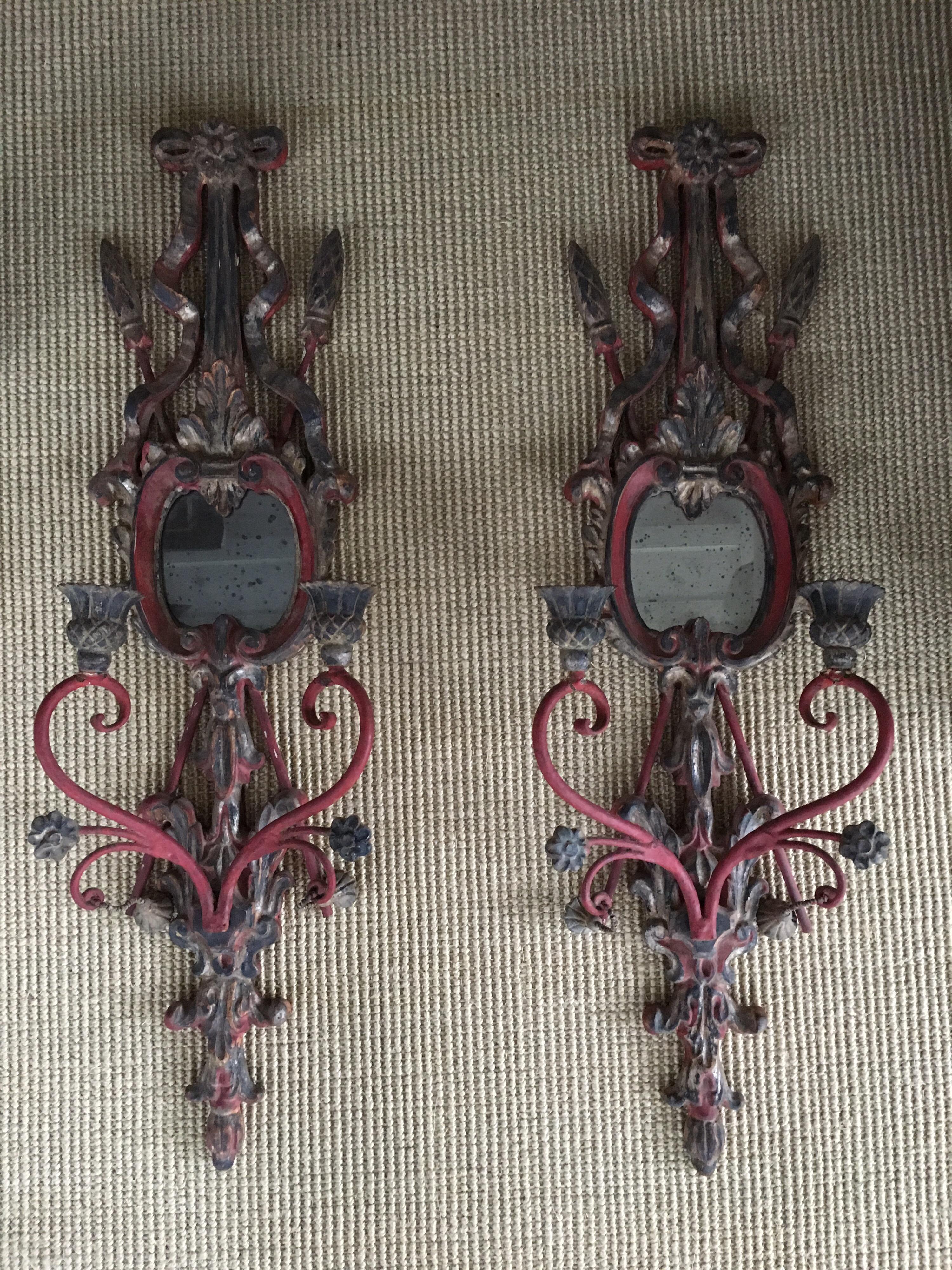 Pair of red carved wood and iron candle wall sconces with old mirror glass.