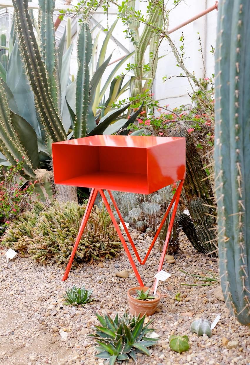 A pair of red Robot bedside tables. The Robot side table features an open shelf on zig zag legs. A fun and functional design made of solid steel, powder-coated in red. The clean lines look great against period details as well as in modern spaces.