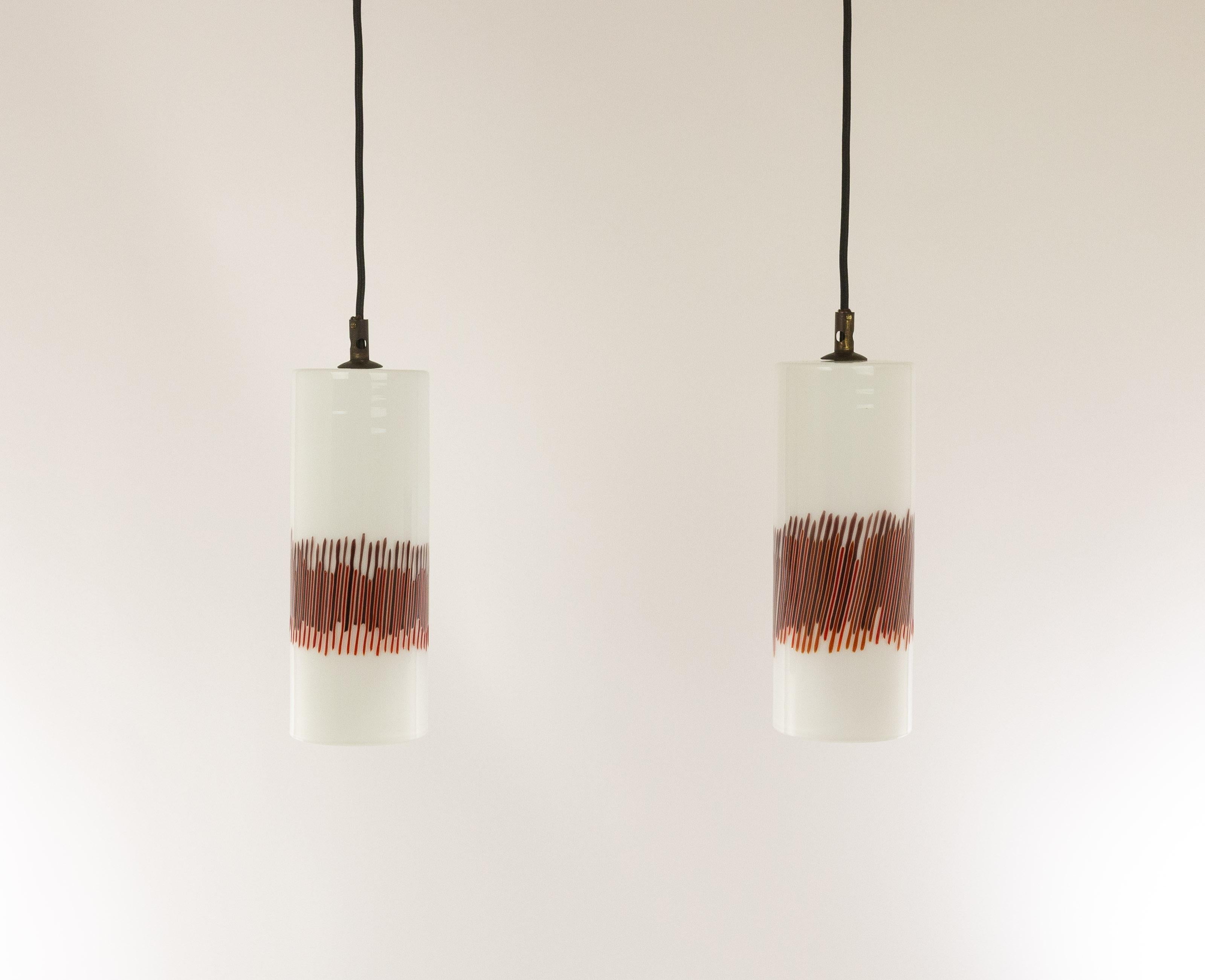 A pair of hand blown white and red striped glass pendants designed by Massimo Vignelli at the start of his impressive career in design and executed by Murano glass specialist Venini.