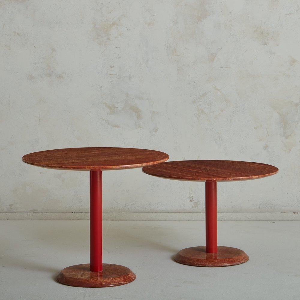 A pair of 1980s side tables by Cattelan Italia featuring round red travertine tops and bases with gorgeous veining. This pair stands at different heights, allowing them to nest together. They have tubular red metal bases and retain ‘Cattelan Italia’