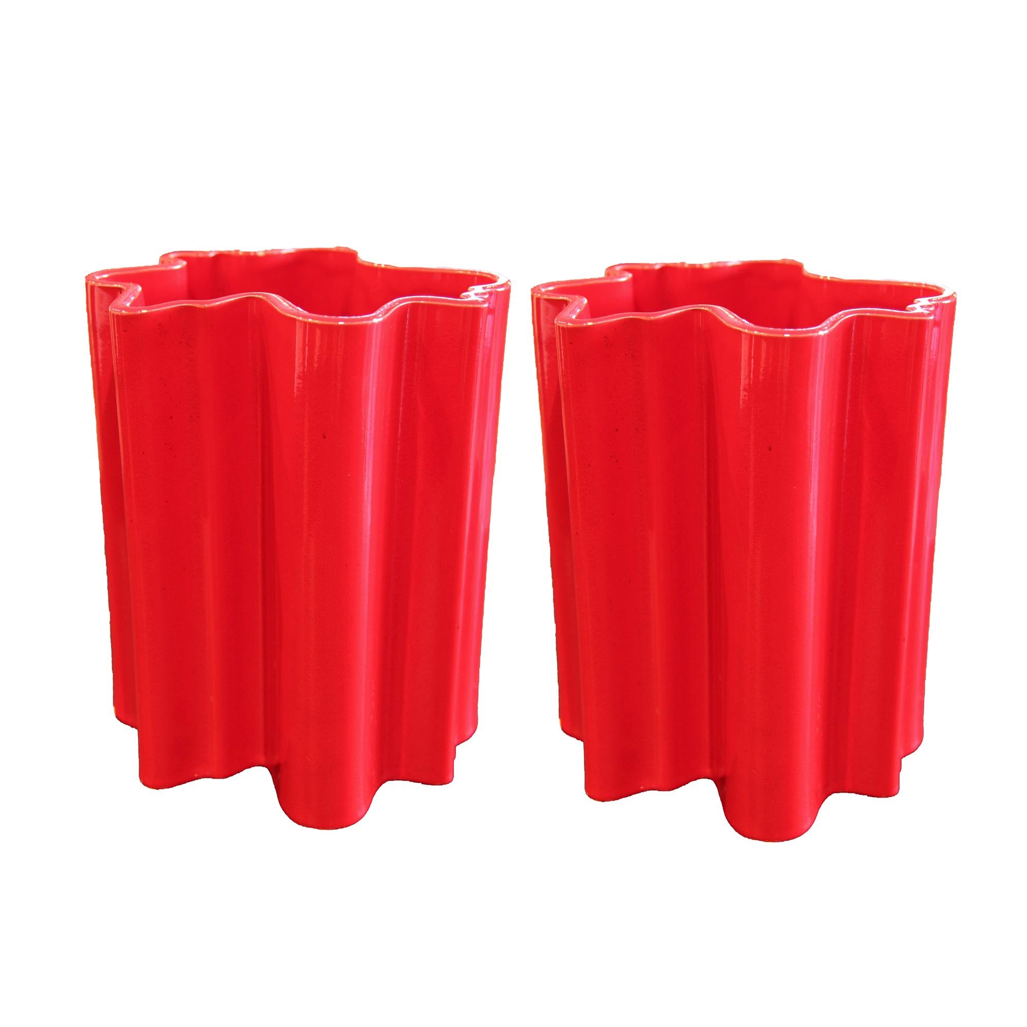Playful pair of bright red glazed ceramic vases. The mouth/opening of each vase has an undulating wave pattern that continues into the rest of the body. These iconic vases are part of the series of vessels designed by Italian architect Angelo