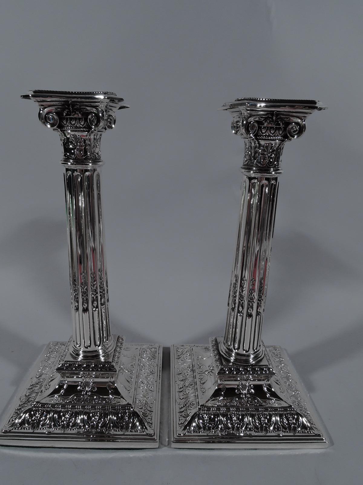Pair of Edwardian sterling silver candlesticks. Made by Reed & Barton in Taunton, Mass., circa 1910. Each: Classical column with stop fluting and ionic capital. Base raised and square and bobeche detachable. Low relief ornament including