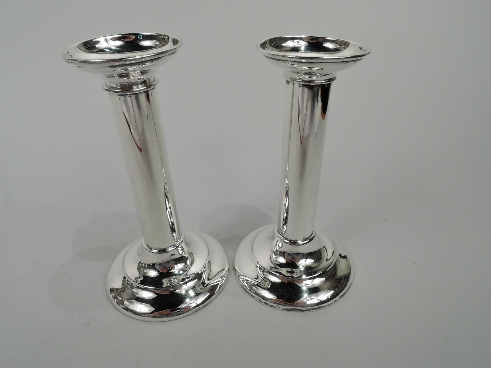 Pair of Edwardian classical sterling silver candlesticks. Made by Reed & Barton in Taunton, Mass., ca 1910. Each: Columnar shaft on stepped and domed foot. Detachable bobeche with flared rim. Ribbon-tied wreath (vacant) engraved on shaft. Fully
