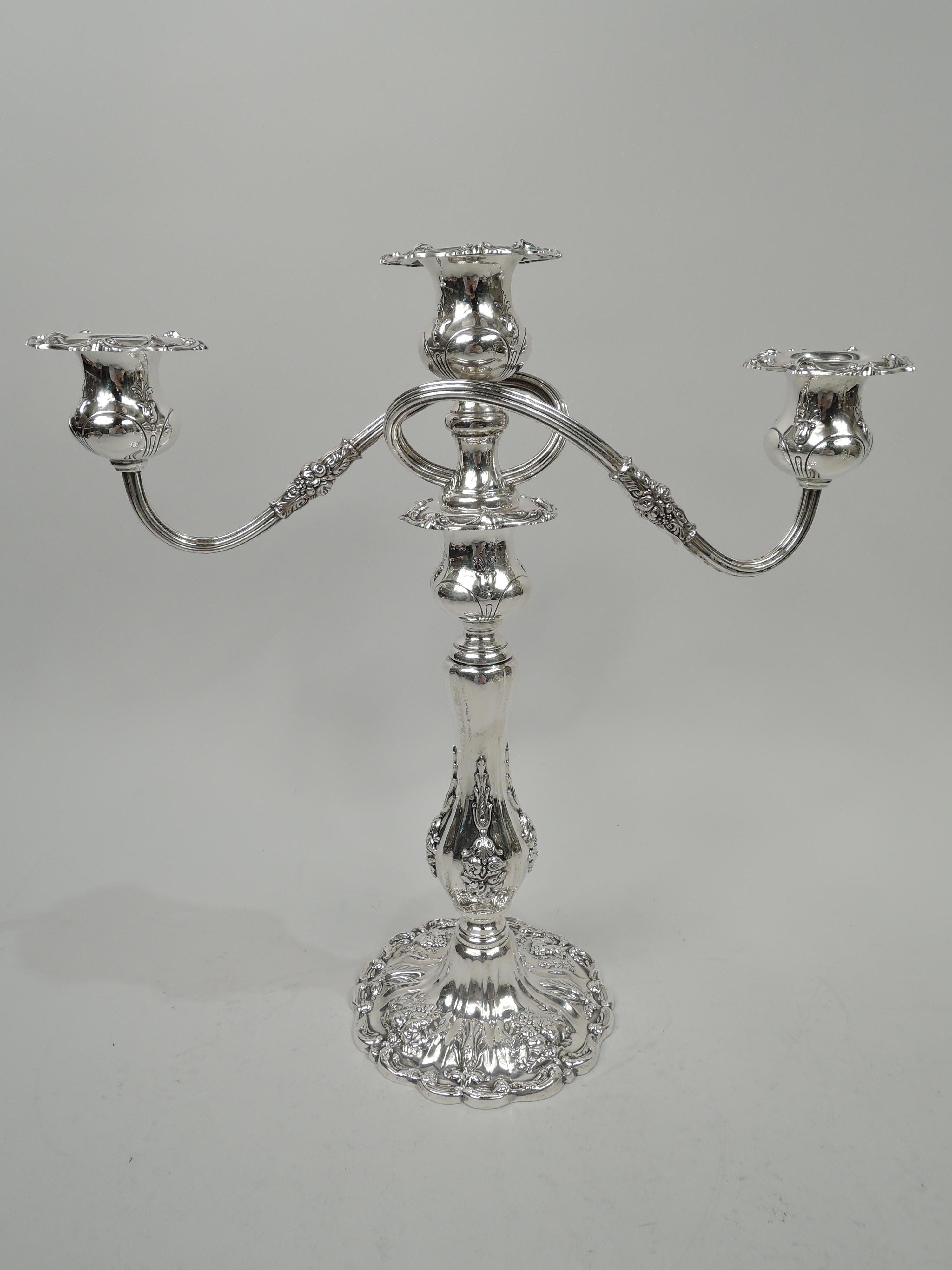 Pair of Francis I sterling silver 3-light candelabra. Made by Reed & Barton in Taunton. Each: Central socket on spool base to which are mounted two reeded wraparound branches, each terminating in single socket. Branches have short leaf and flower