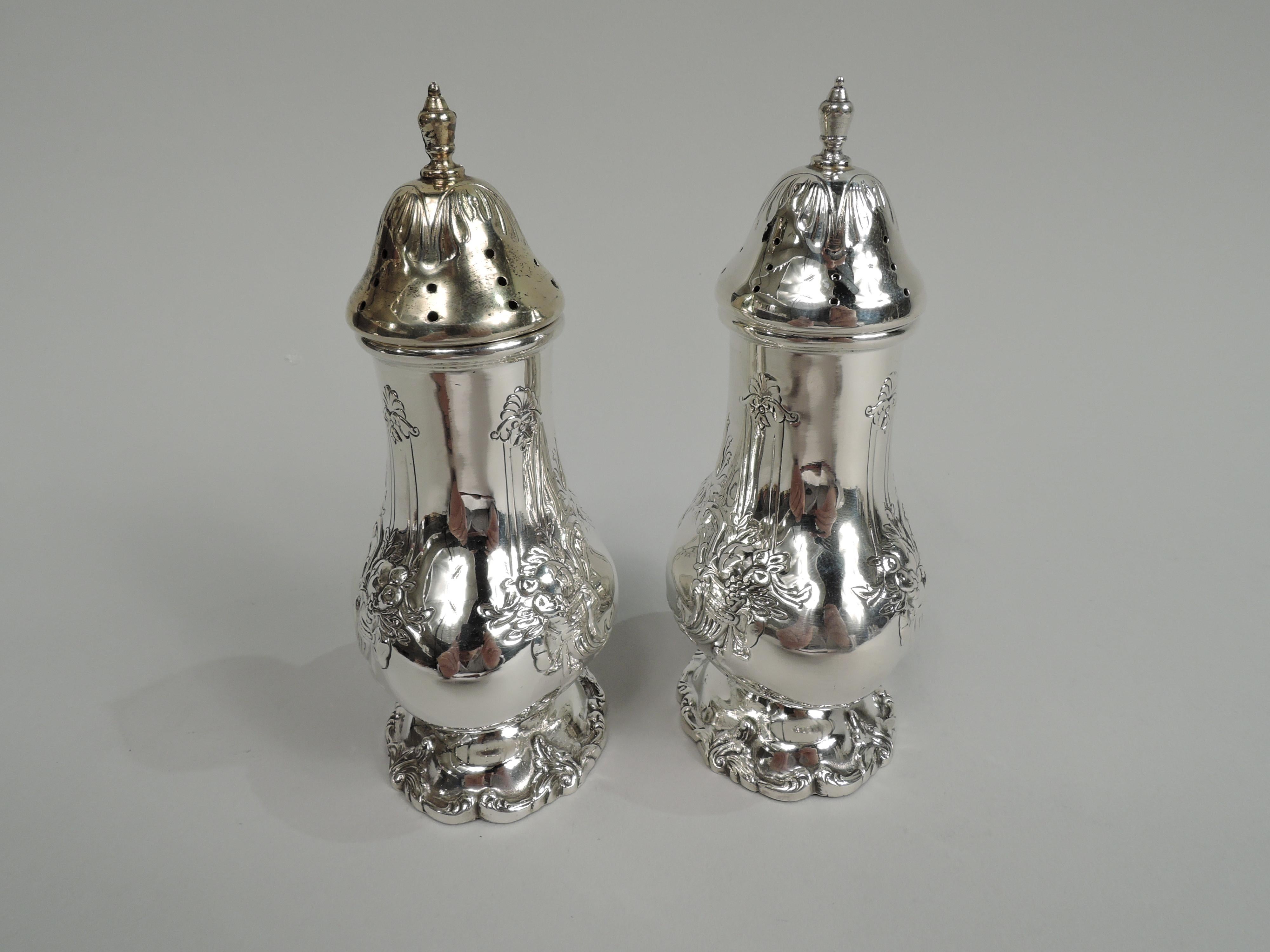 Pair of Francis I sterling silver salt and pepper shakers. Made by Reed & Barton in Taunton, Mass. Each: Oval and bellied on raised foot. Cover domed and pierced with vasiform finial; one cover gilt. On front and back are chased strapwork cartouches