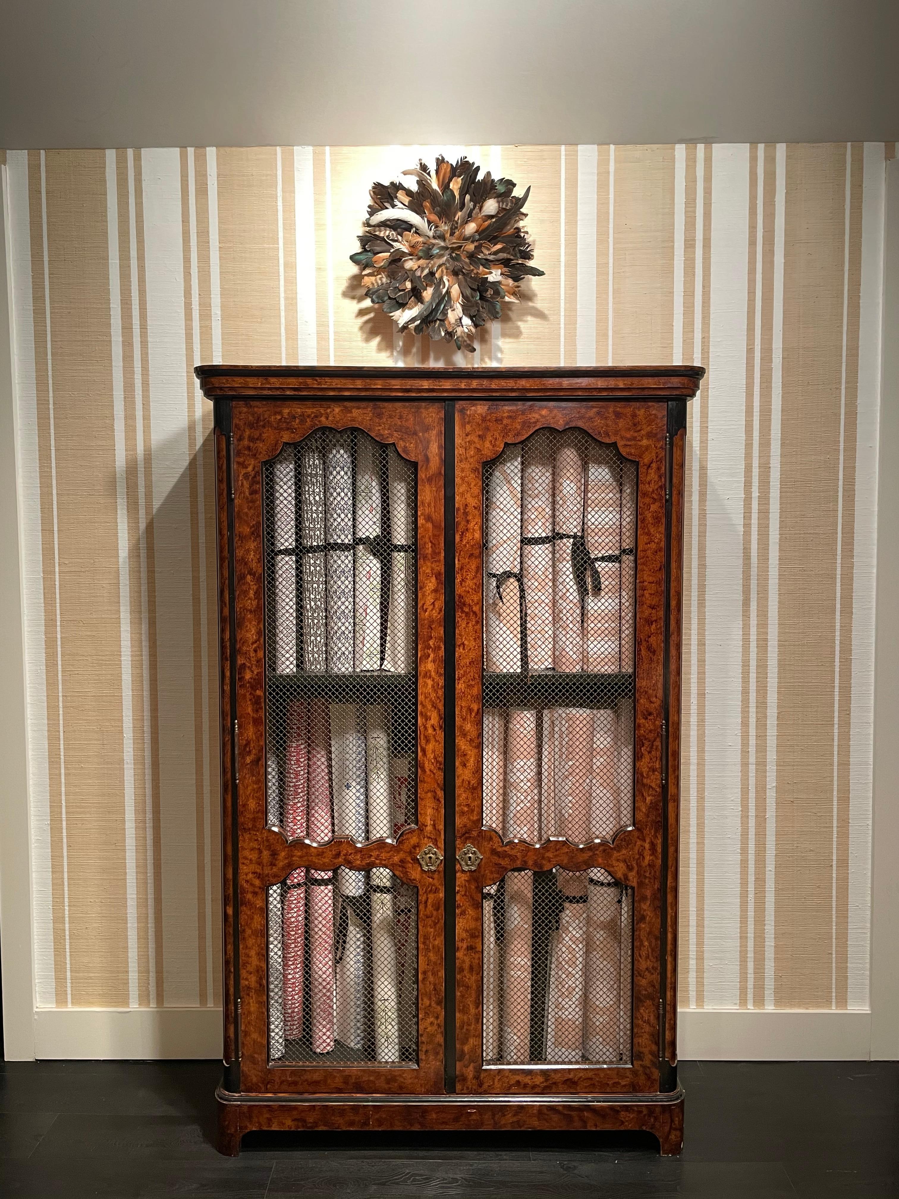 A pair of Regence style faux bois painted bookcases with ebonized banding on upper cornice above two wired panelled doors opening to reveal ebonized interior shelving on molded plinth with block feet.