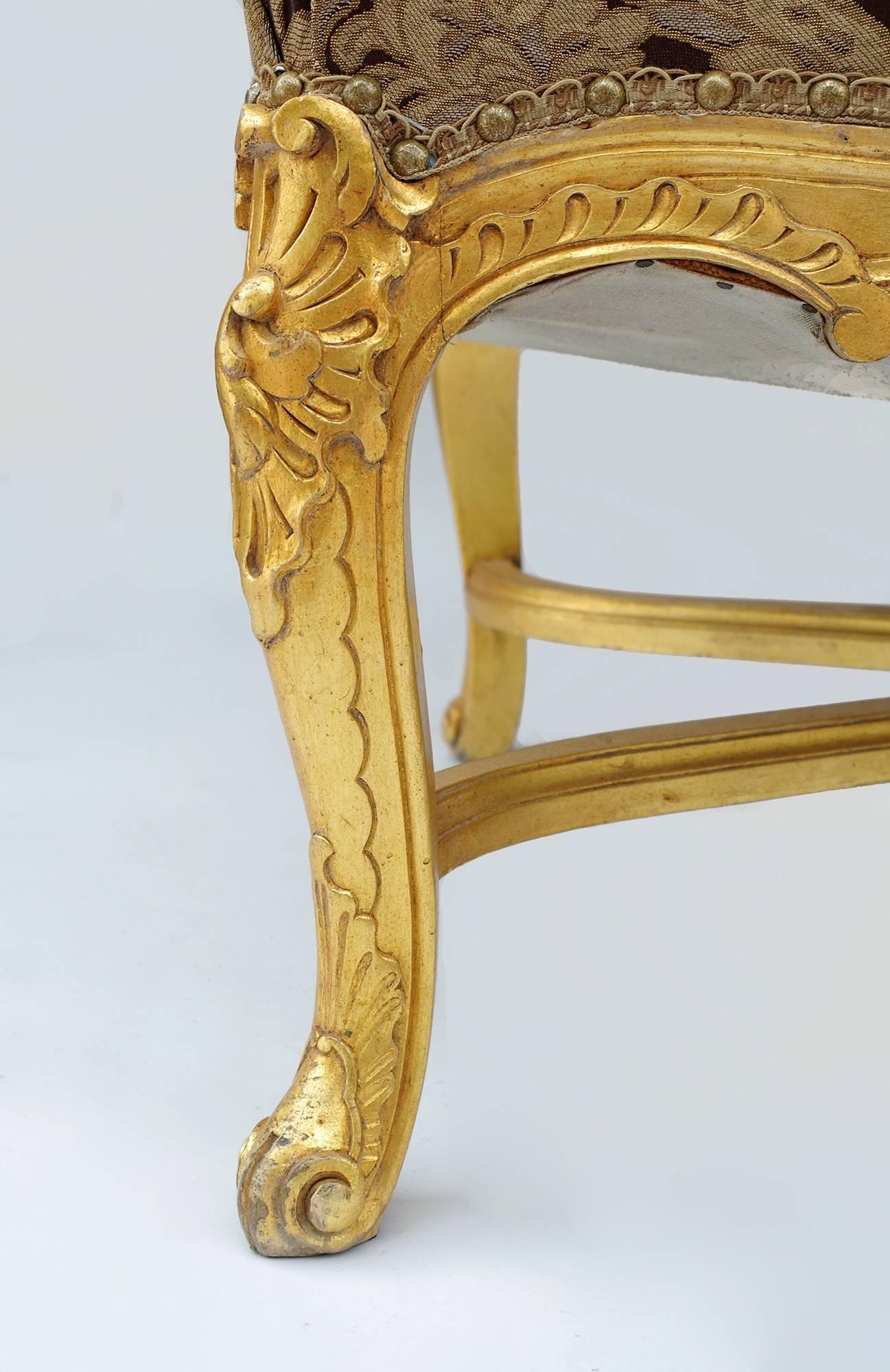 Pair of Regence style giltwood high back à la reine armchairs. They stand on four curved legs connected by a spacer, in the classical style of the Regence. The legs, armrests and the apron are decorated by acanthus leaves, shells and 