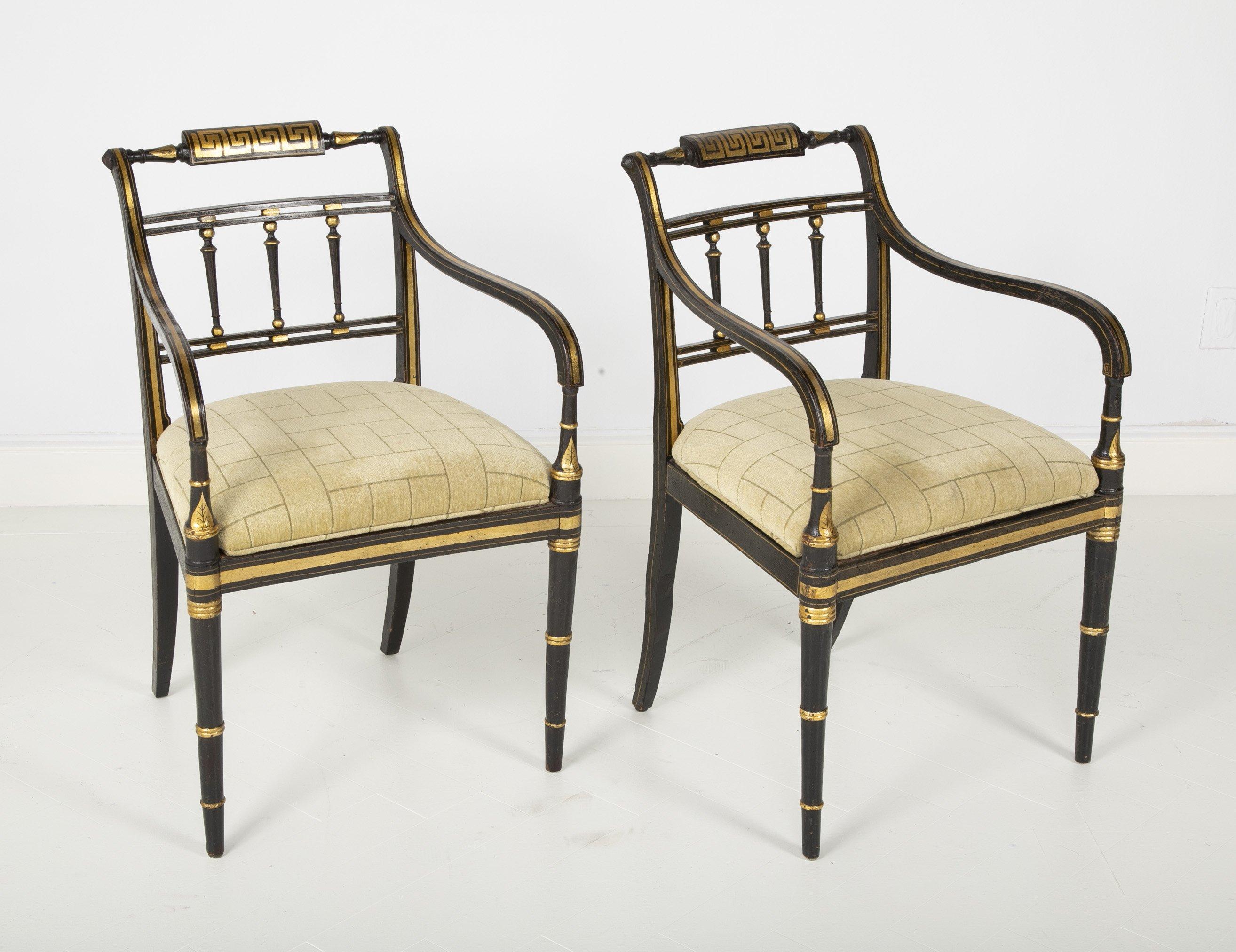 Pair of English Regency painted and gilded armchairs with Greek key motif decoration, turned splat supports and faux bamboo legs. The seats are covered with upholstered cushions.
 
  