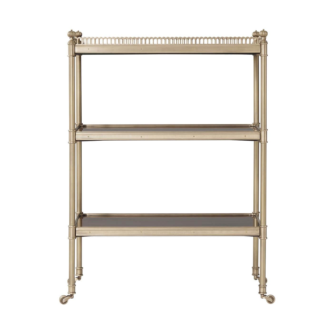 An English Regency style morado and brass three-tier low etagere, the rectangular pierced repeating arch brass gallery top and brass bound lower tiers between brass columns terminating in brass castors. 

Dimensions: 21