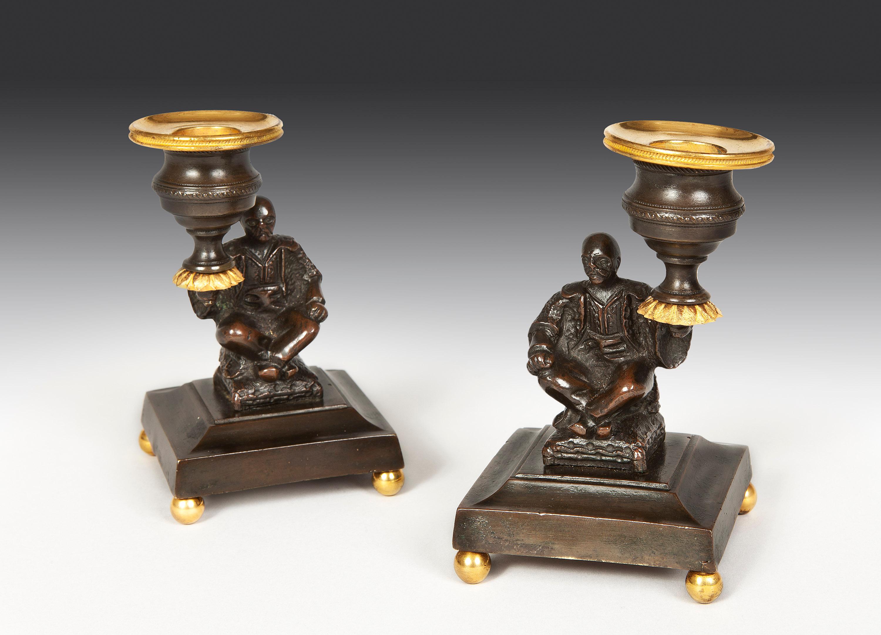 Each candlestick has a bronze Chinaman sitting cross-legged on a fusion holding a candle branch aloft.