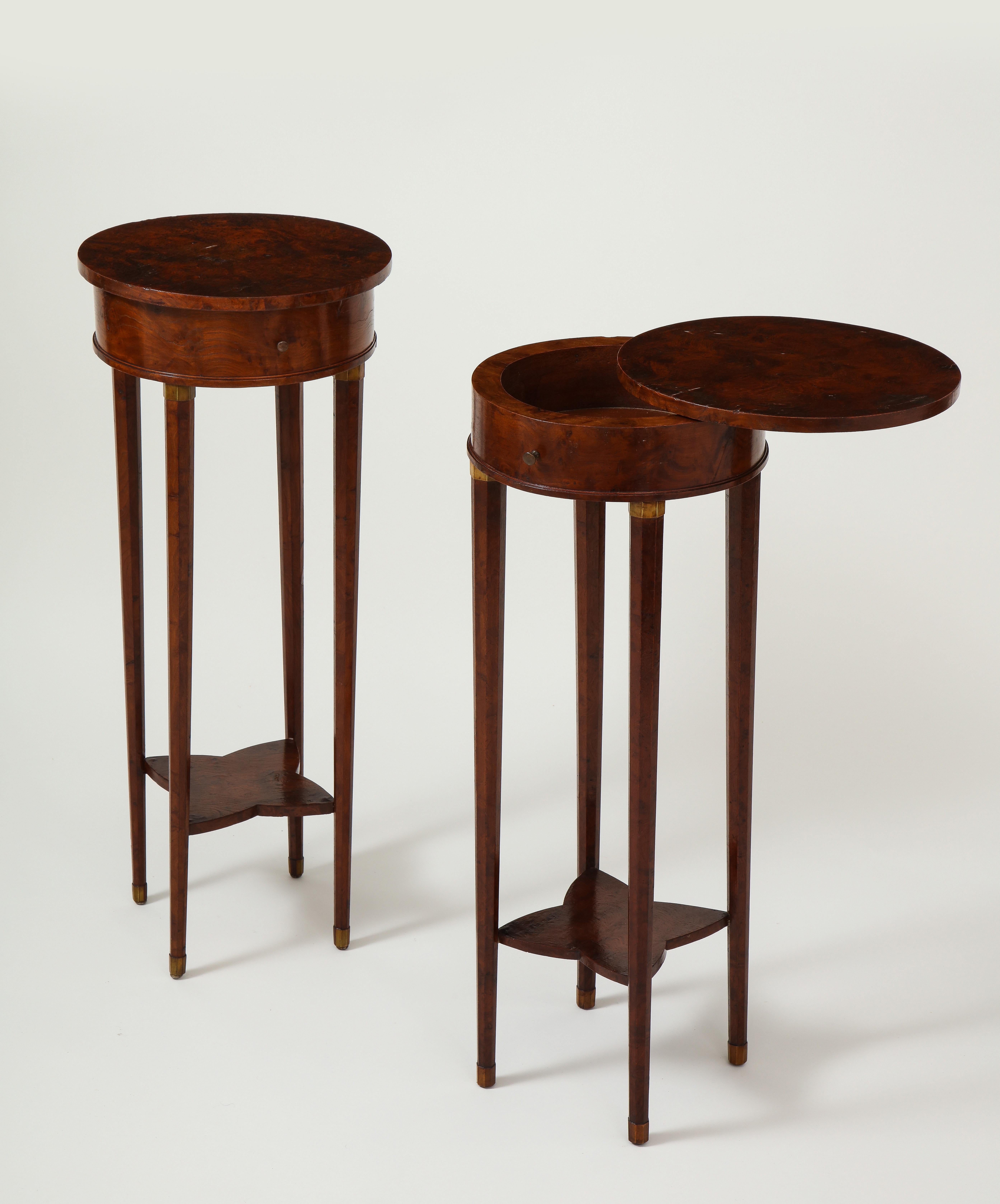 Each with round highly figured top that slide to reveal the interior; raised on tapering legs with fruitwood capitals and feet to simulate brass mounts; joined by shaped platform stretchers.