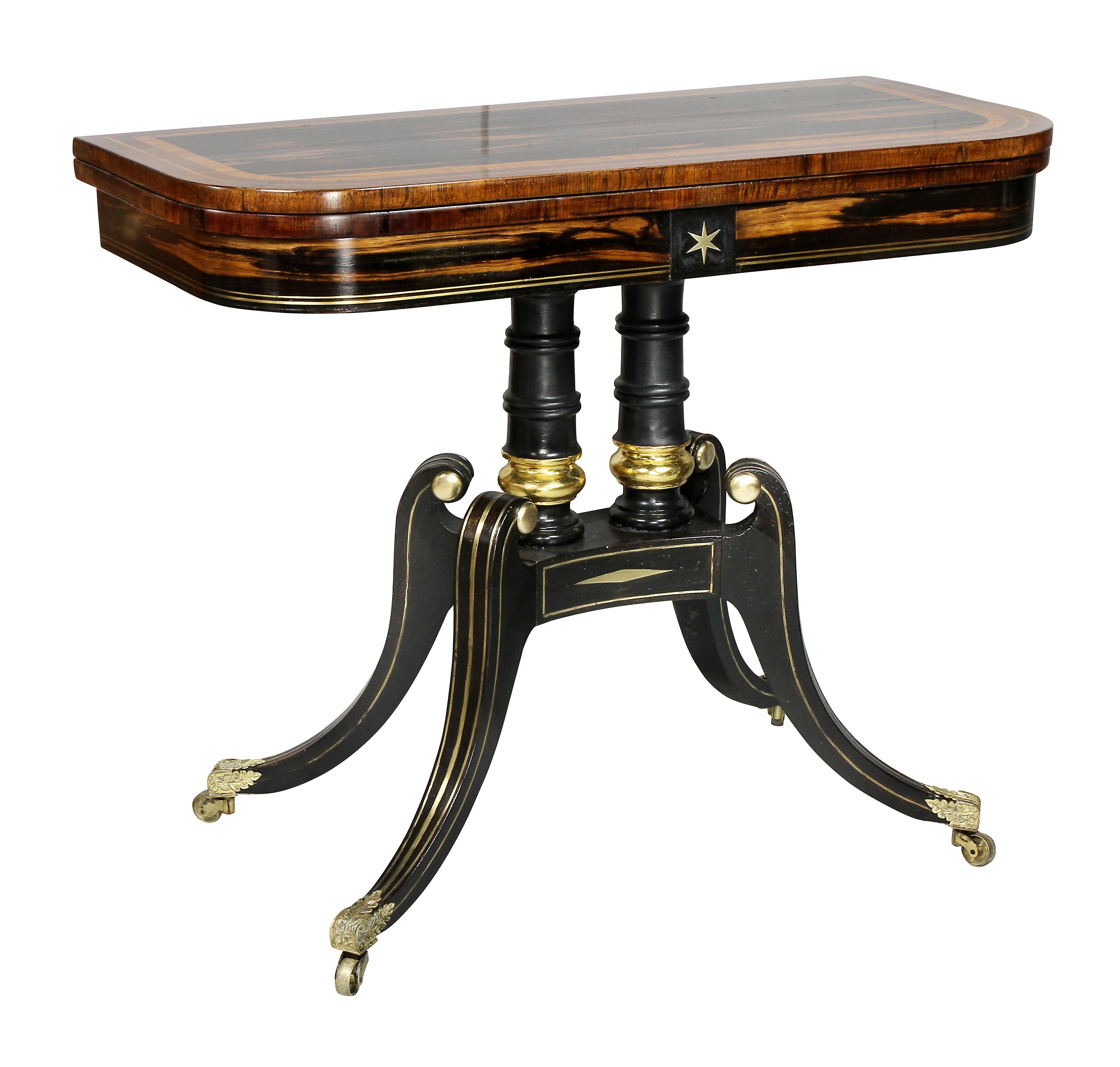 Each with a hinged rectangular top with rounded corners and satinwood inner banding, opening to a leather lined playing surface, over a frieze with central inset brass star, over two turned ebonized and gilt supports raised on four brass inlaid