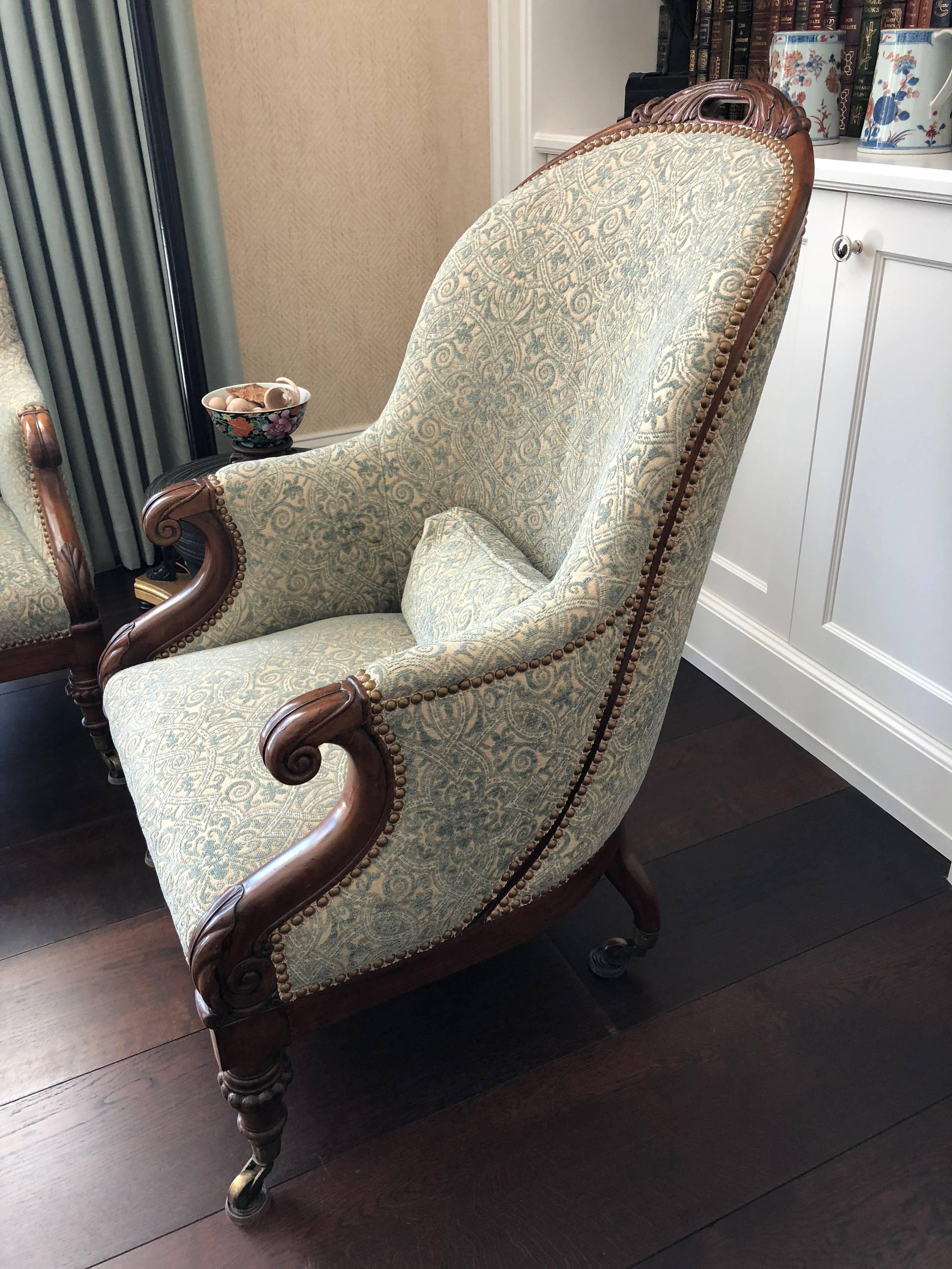 The pair of Regency club armchairs
hand made of mahogany with rounded backs, upholstered with small pillows to match hand-carved hand rests and their supports on turned short feet brass casters purchased from Florian Papp, New York.