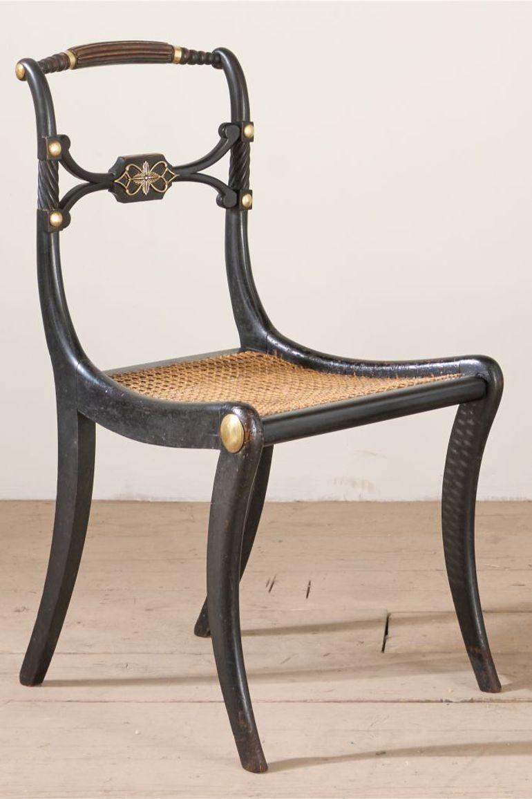 These are a very nice pair of sabre legged Regency period side chairs. The have a very attractive worn original ebonised finish. The brass details all over are also original but some have been reattached through their life. There is also a brass