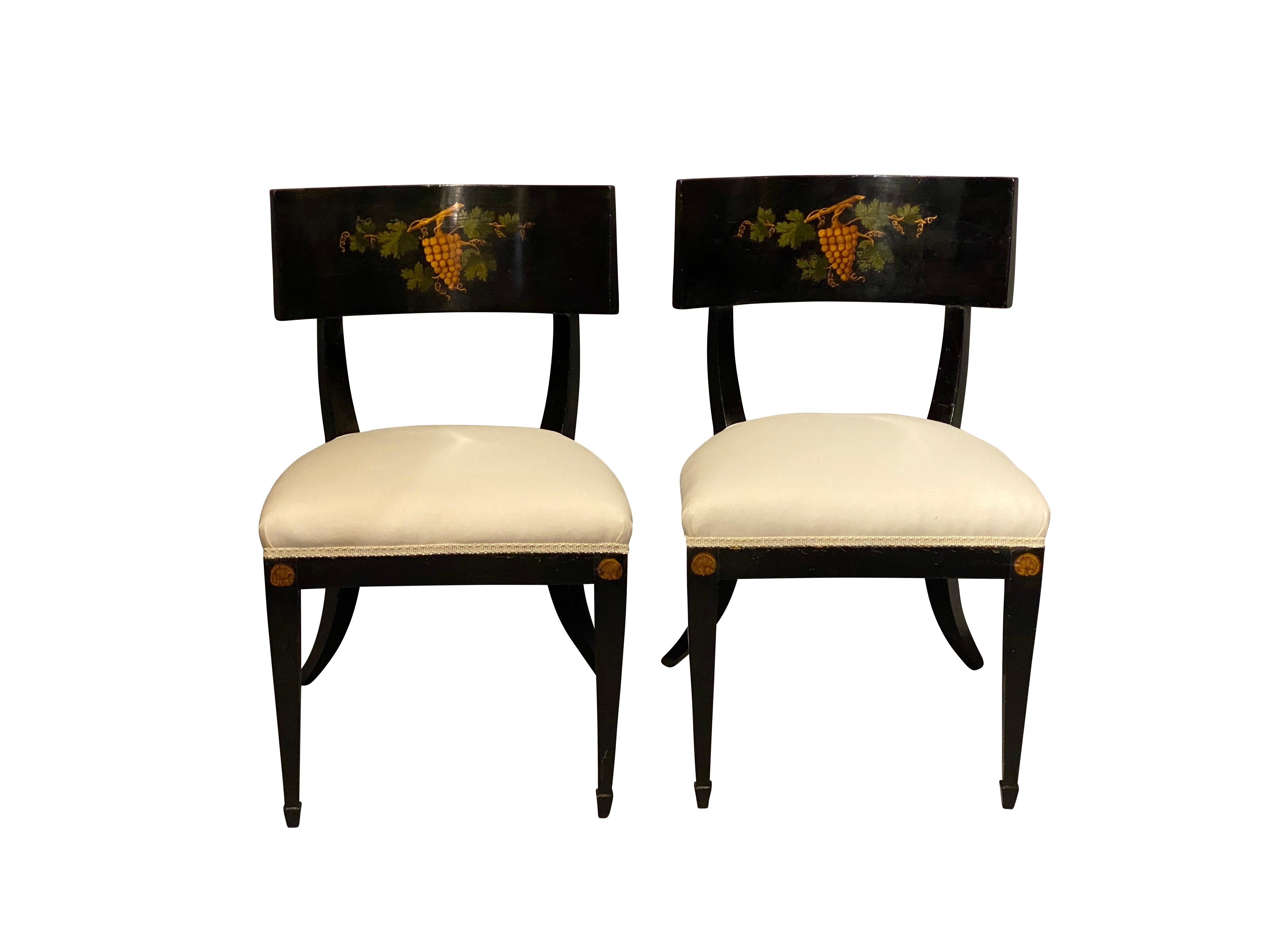 Each with a curved wide seat rail with grape leaves and grapes central decoration, upholstered seat, raised on exaggerated saber legs. Provenance; Estate of William Hodgins, Interior designer. Boston.