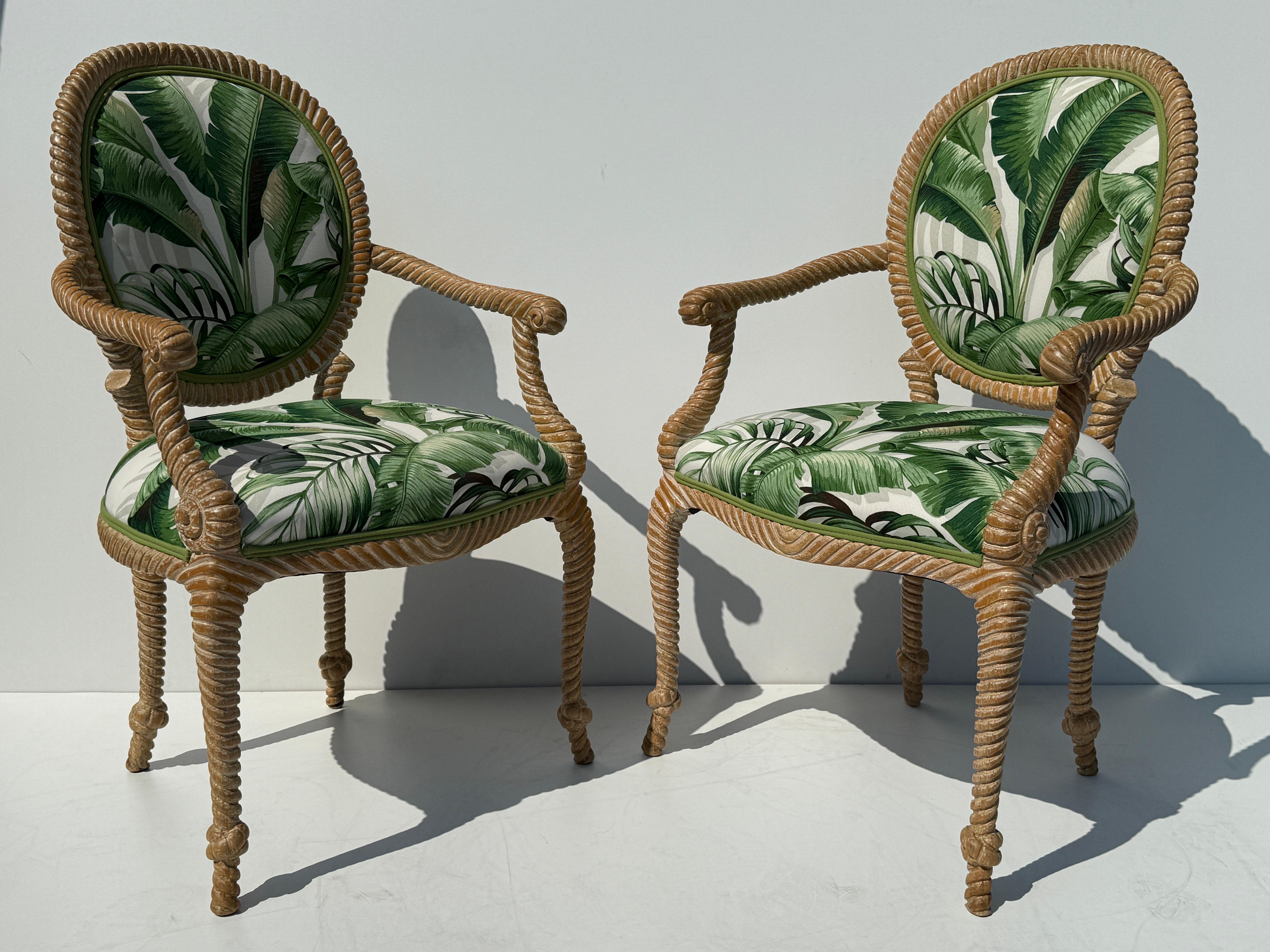 Pair of Palm Beach Regency faux bois hand carved rope and tassel armchairs in weathered white wash finish and upholstered in tropical banana leaf print fabric.