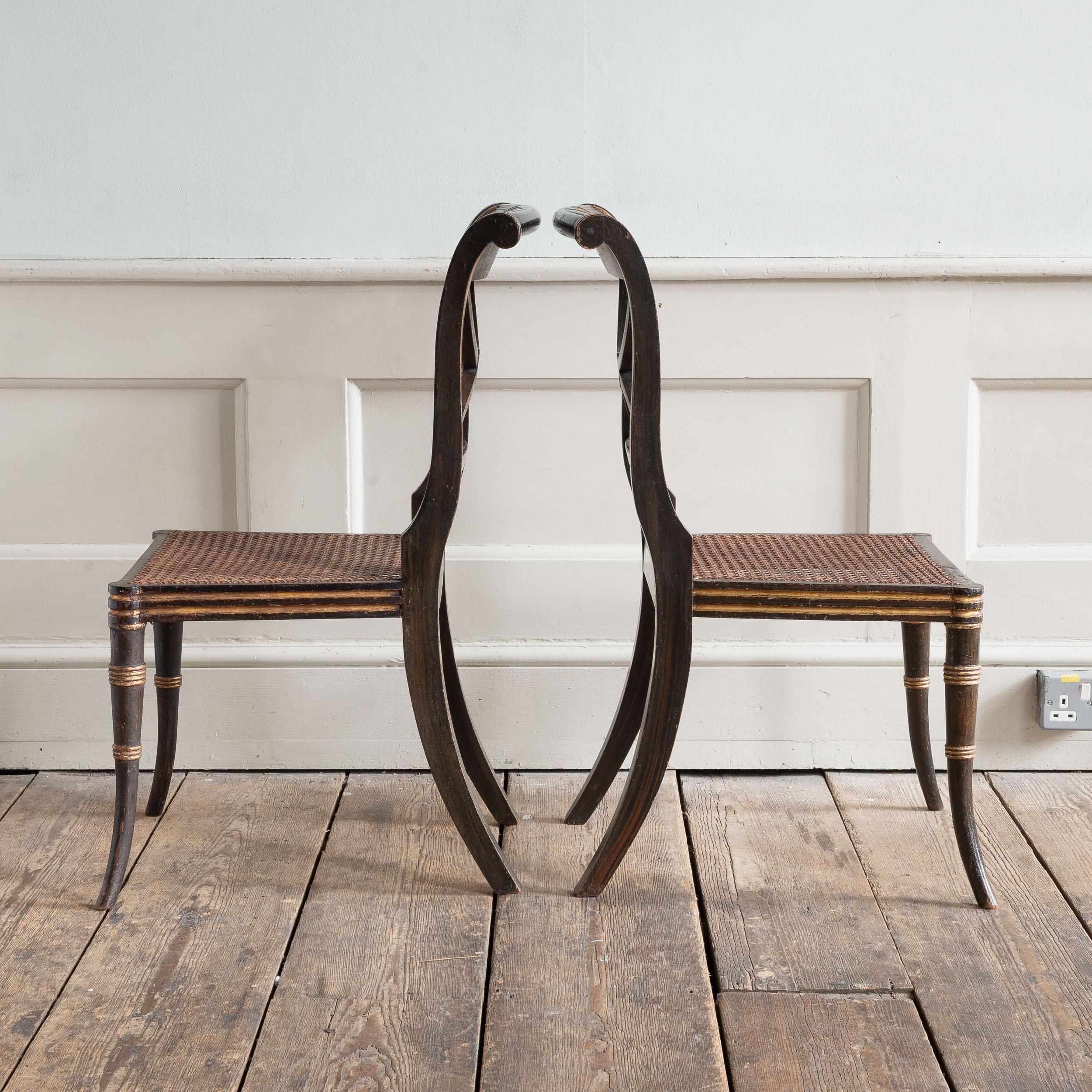 Paire de chaises d'appoint Regency anglaises en faux bois de rose et colis dorés, les traverses supérieures ornées de charmants et naïfs portraits de lions peints flanqués d'un anthemion, les sièges cannelés, les pieds avant évasés et les pieds