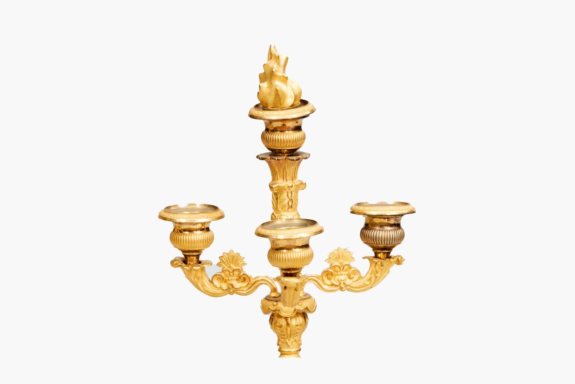 Pair of Regency French ormolu gilded candelabras featuring Turkish figures supporting three foliate carved candle branches with urn-shaped bobeches. On both, the central stem is topped with an ornamental gilt-bronze flame that can be removed and an