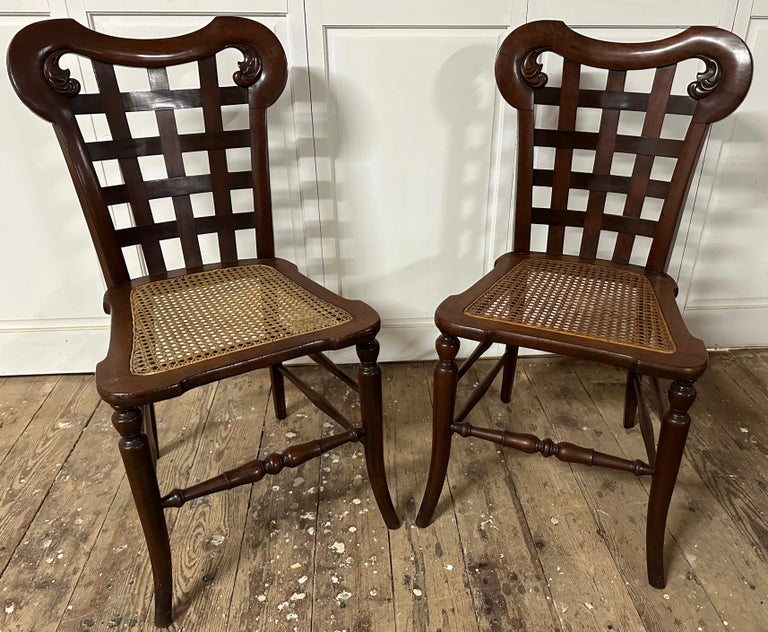 A unique and unusual pair of 20th Century Regency inspired mahogany side chairs with caned seats with carved woven wood back.  Use these chairs as extra seating or accent chairs in any room, a pair of dining chairs around a small kitchen table or as