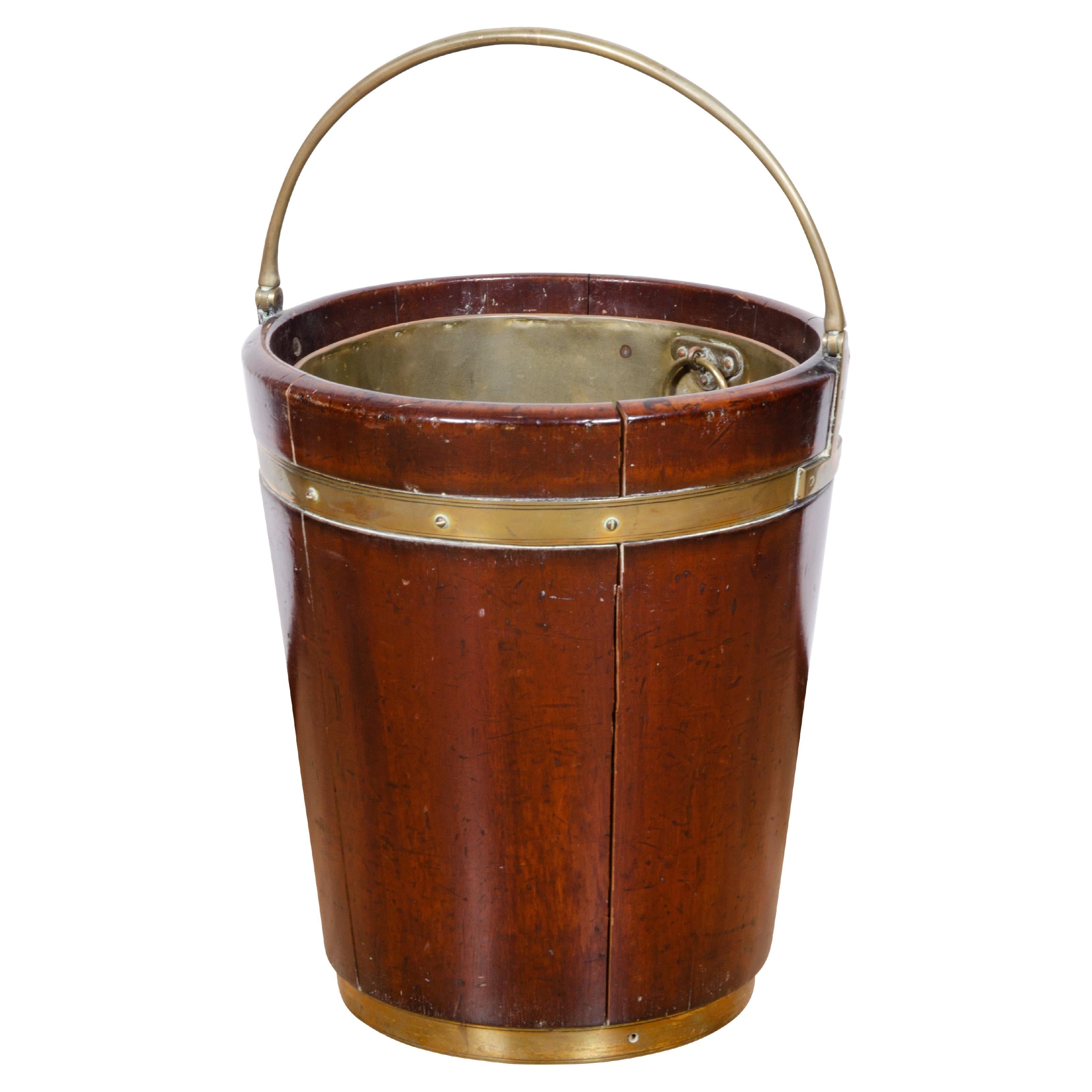Each with brass bail handle and cylindrical bucket with brass liners and outer strapping. One bucket with notched side to serve a dual purpose as a plate carrier. Lovely on either side of a fireplace. Handle up height 24.75.