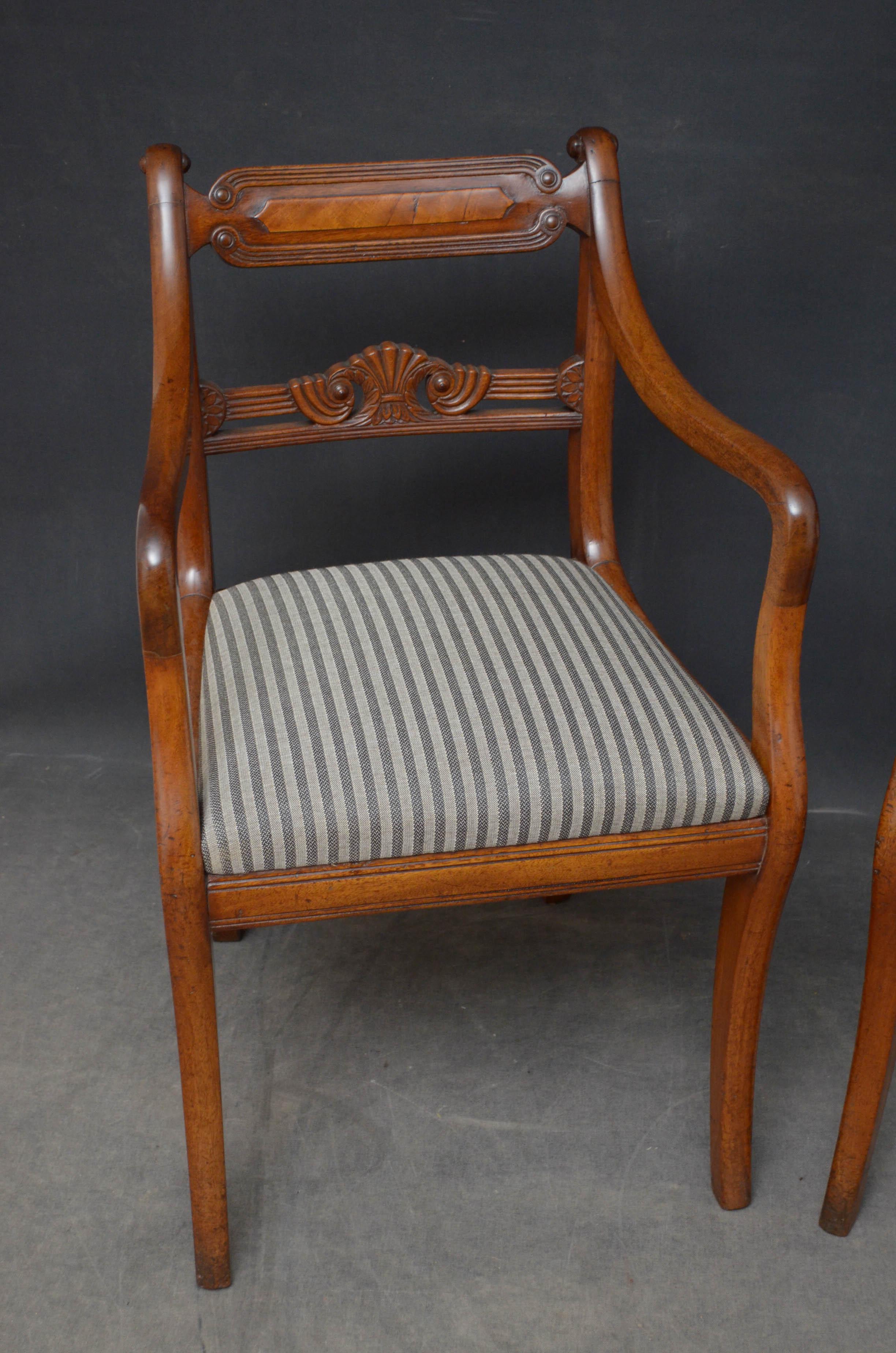 Sn4785 Fine quality Regency elbow chairs in mahogany, each having shaped and reeded top rail above finely carved mid rails, newly upholstered drop in seat and open arms, standing on sabre legs. This pair of antique carves retains its original finish