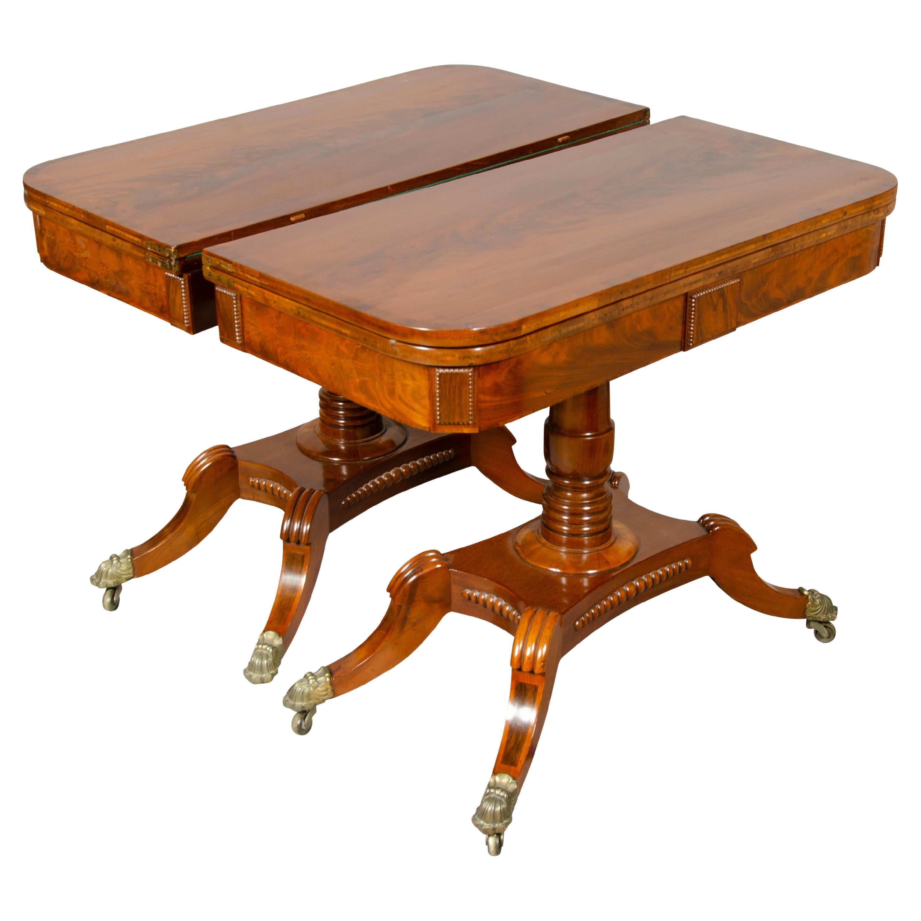 Each with hinged crossbanded top over a frieze with central tablet. Top flips open to a green baize playing surface. The top swivels enabling the top to flip for a card table size surface, raised on a turned support, saber legs and casters.