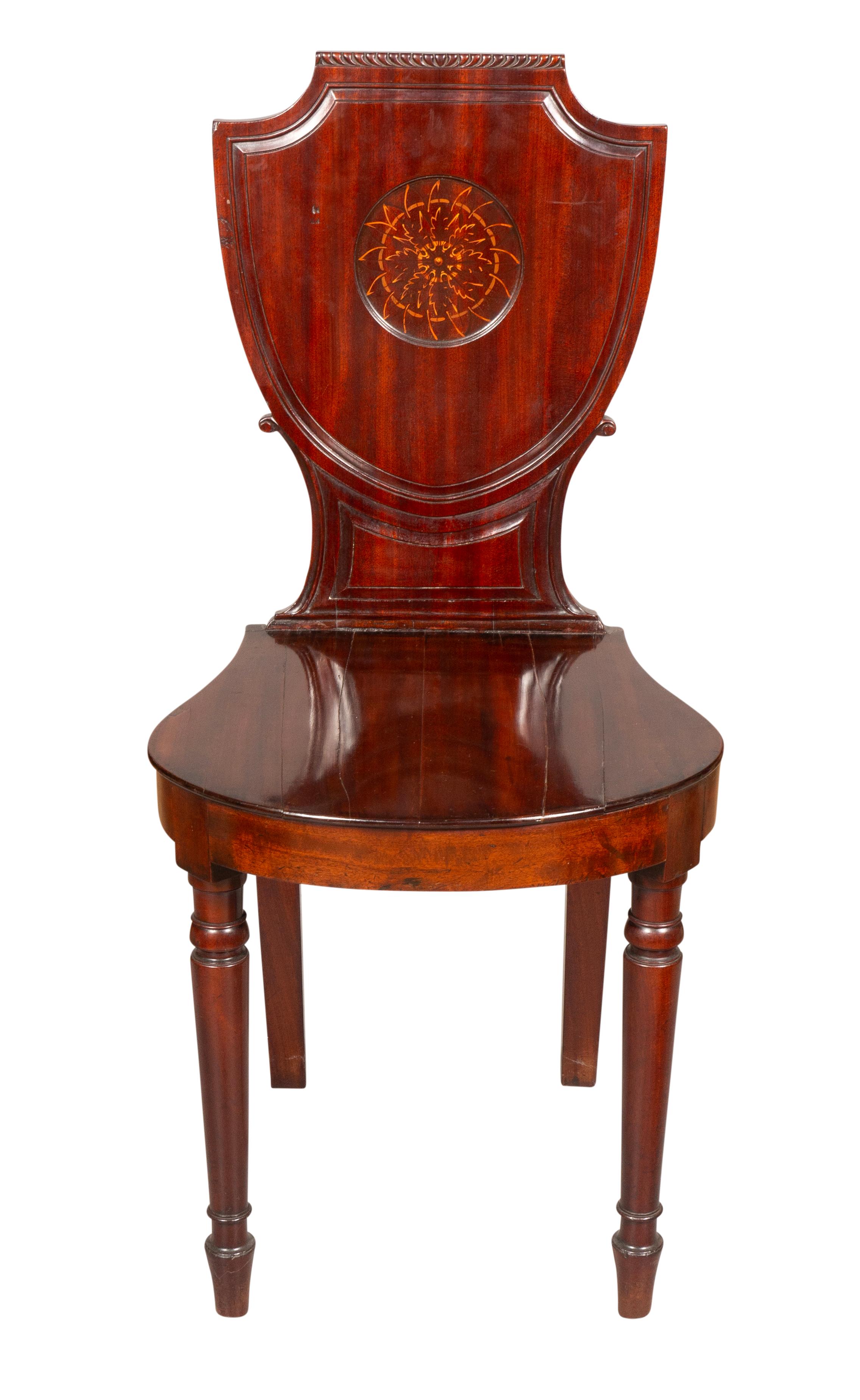 Shield form backs with central painted roundel. The bowed seat raised on circular tapered legs.